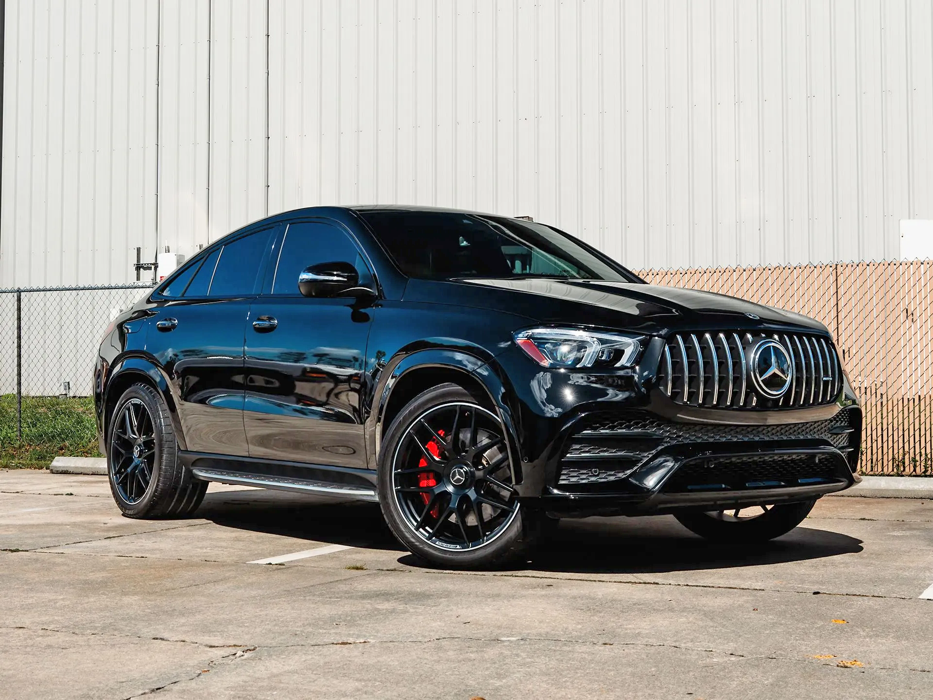 Black Mercedes-Benz GLE Coupe parked on asphalt. Red brake calipers visible behind black wheels.