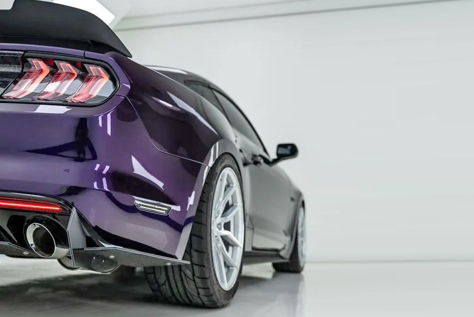 Purple sports car, rear view, in a white studio.