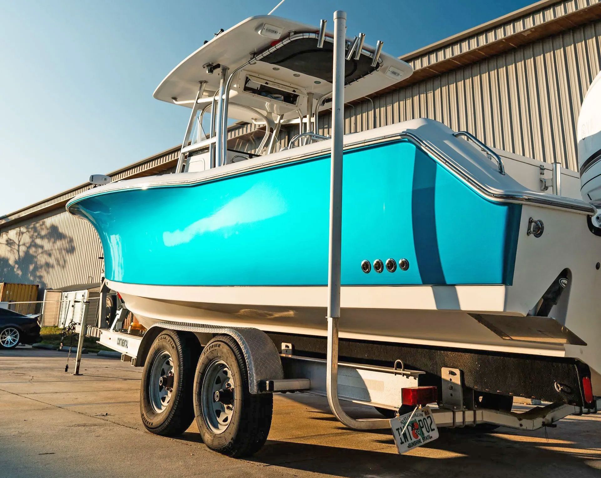 Blue and white motorboat on a trailer, parked outside a building.