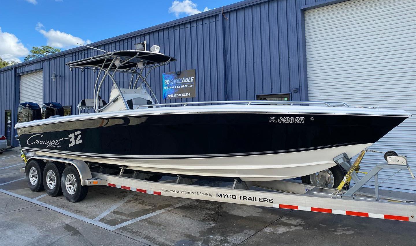 Black and white powerboat on a trailer in front of a blue building with roll-up doors.