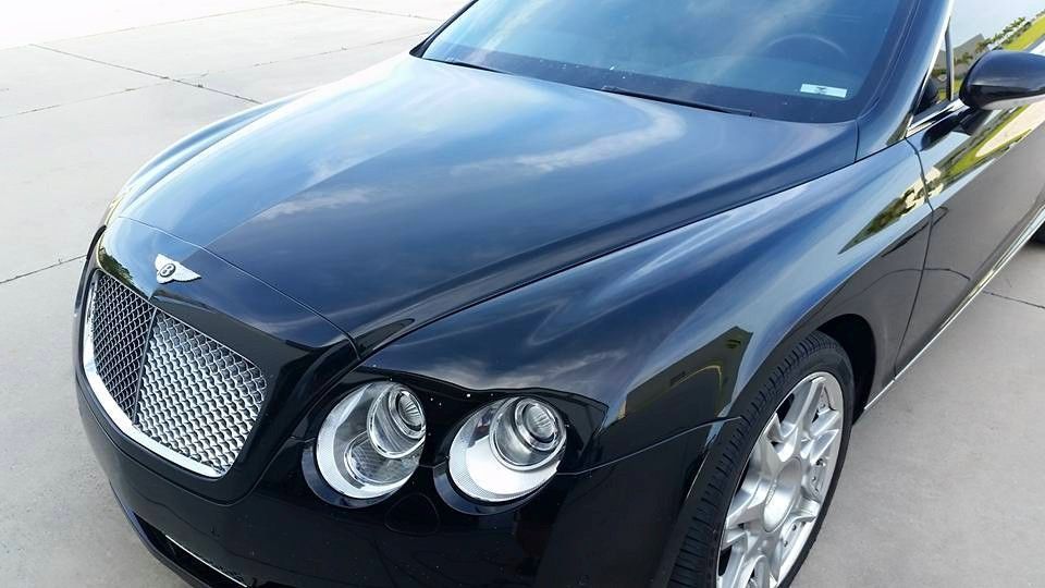 Black Bentley Continental, close-up view of the front. Grille, headlights, and hood details visible.