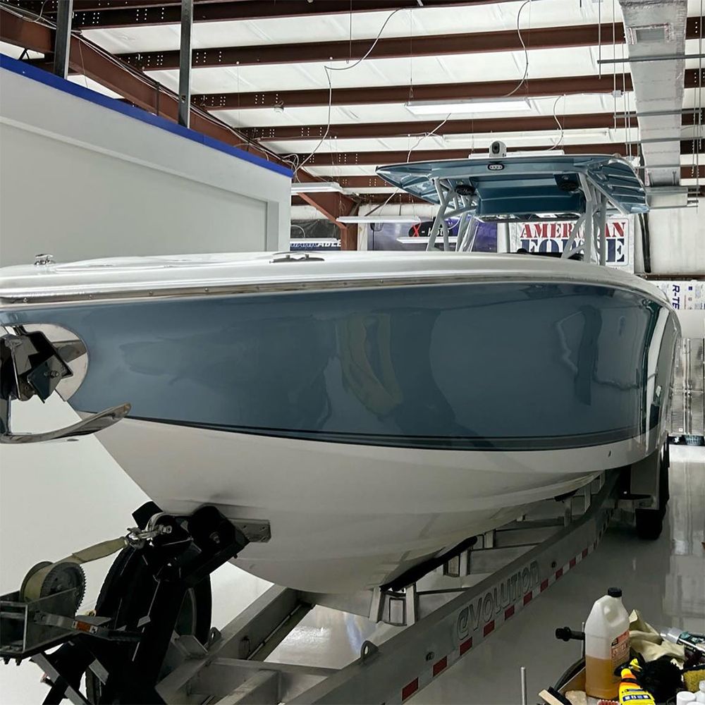 Blue and white boat on a trailer inside a building.