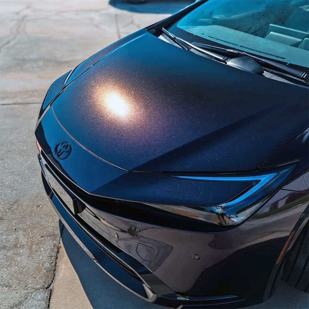 Black Toyota car hood with a color-shifting metallic finish, parked on concrete.