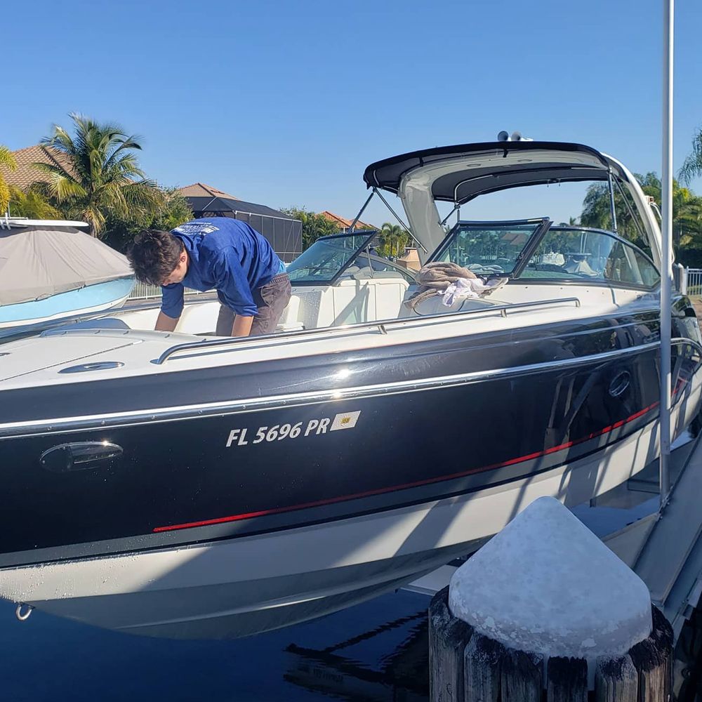 Man on a black and white boat, working on the deck. Florida license plate visible. Sunny day at dock.