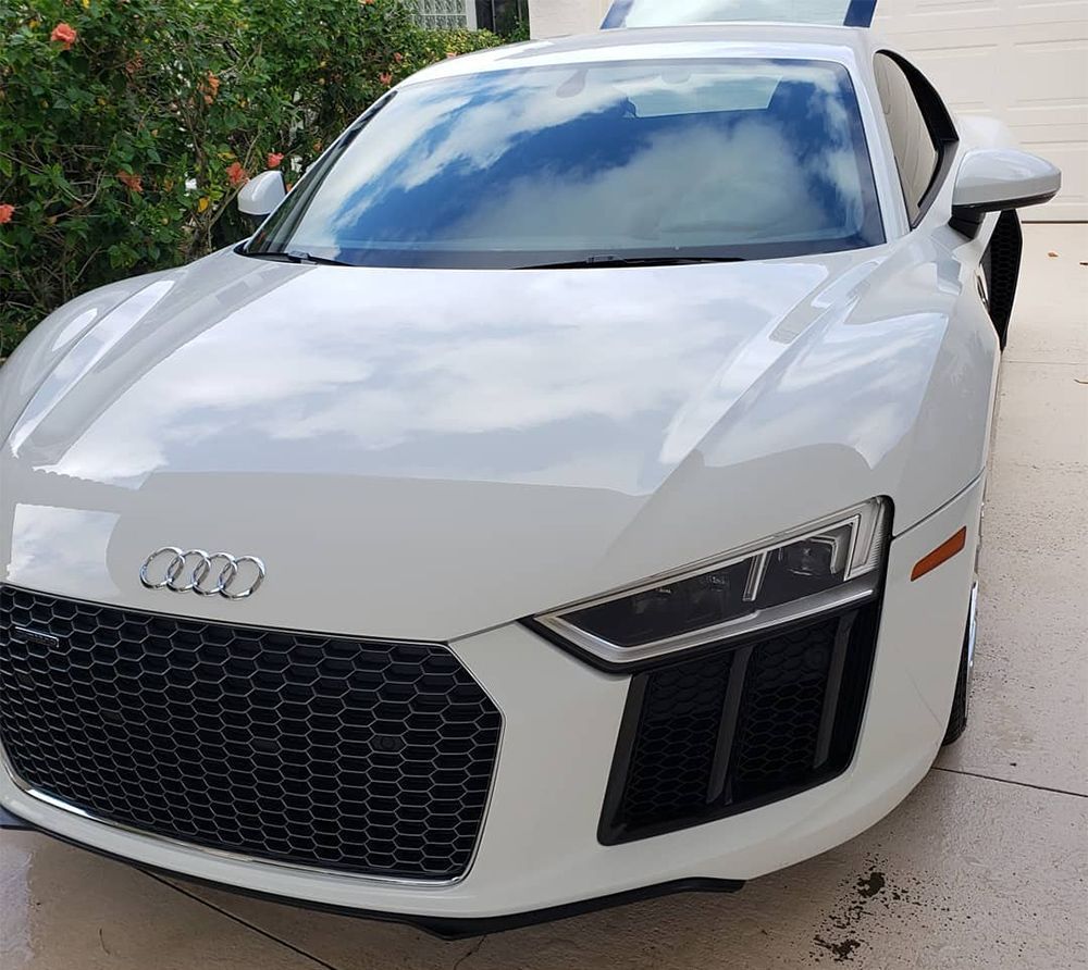 White Audi R8 sports car, parked outside on a sunny day.