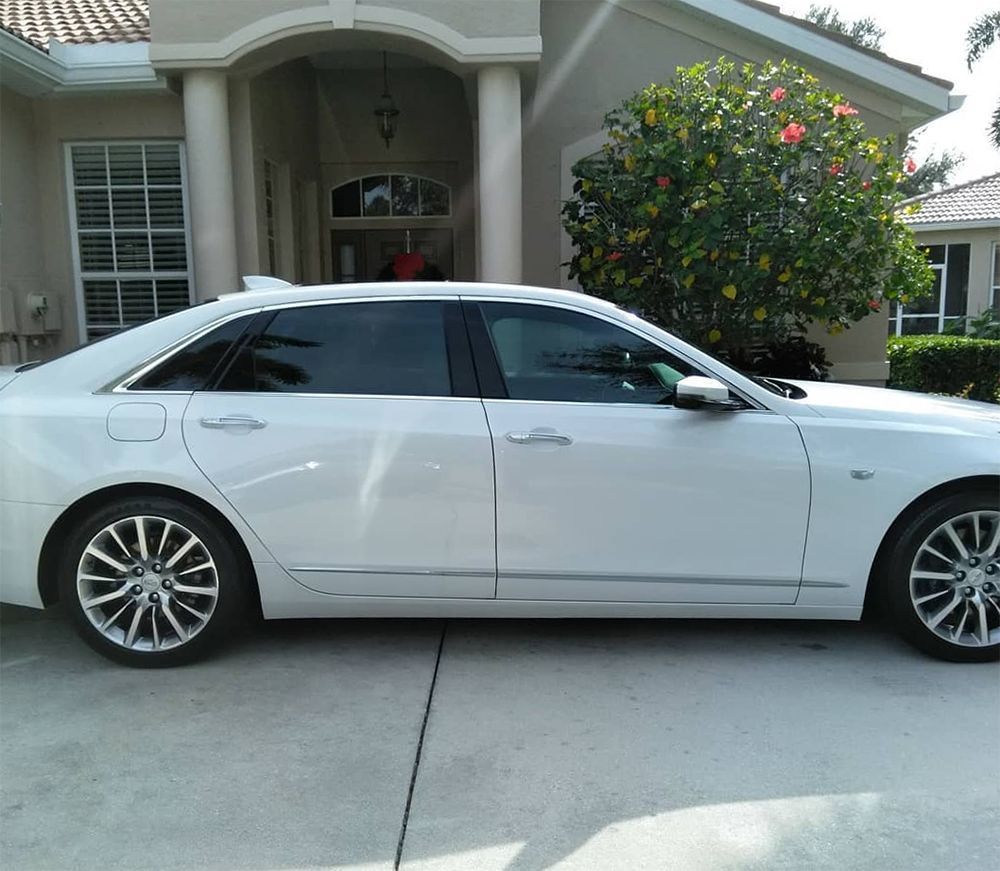 White sedan with tinted windows parked in front of a house.