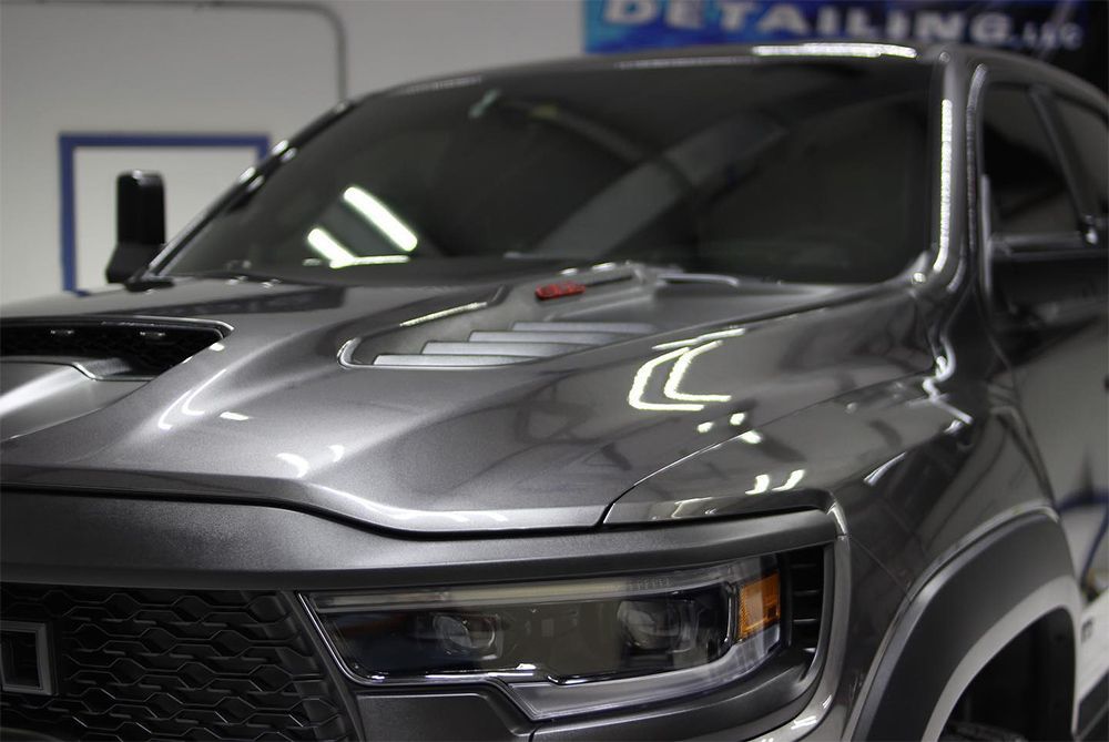 Gray pickup truck hood with air vents and a headlight.