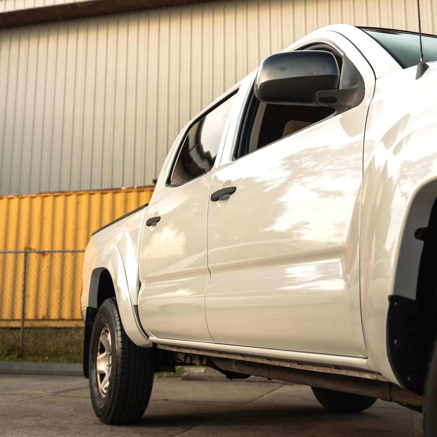 White pickup truck parked in front of a yellow storage container.