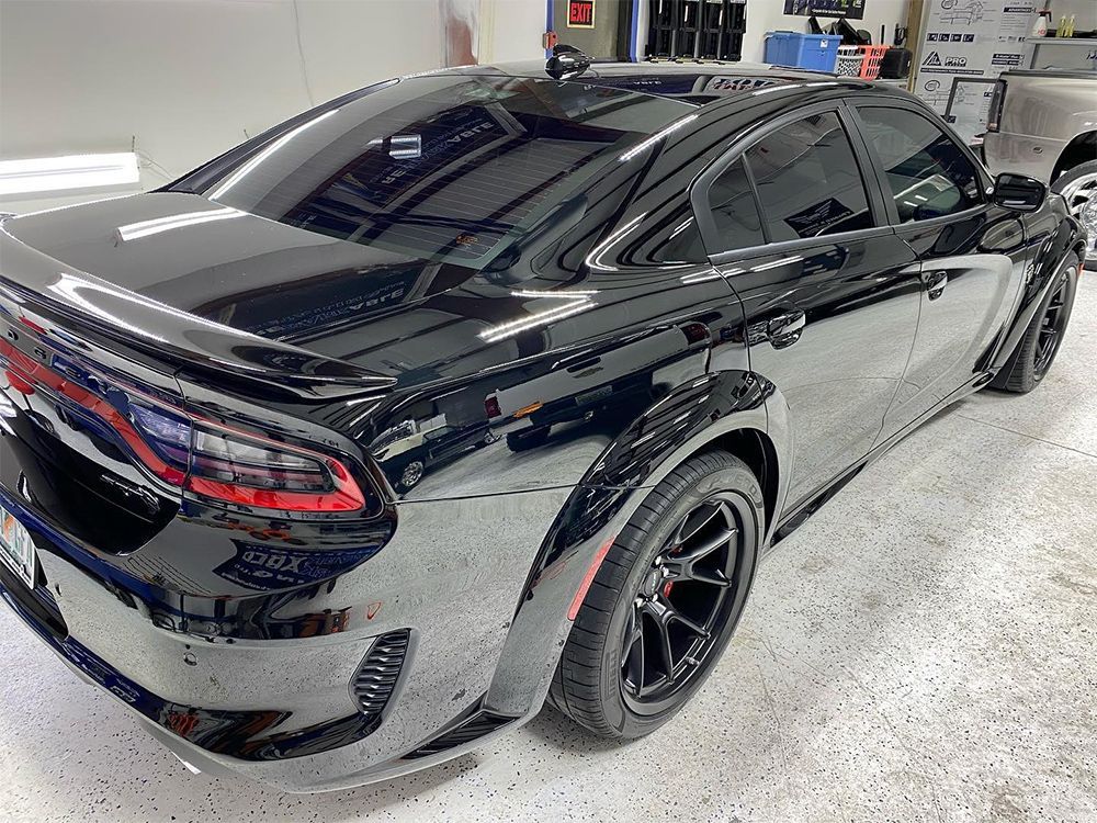 Black Dodge Charger with tinted windows, parked indoors.