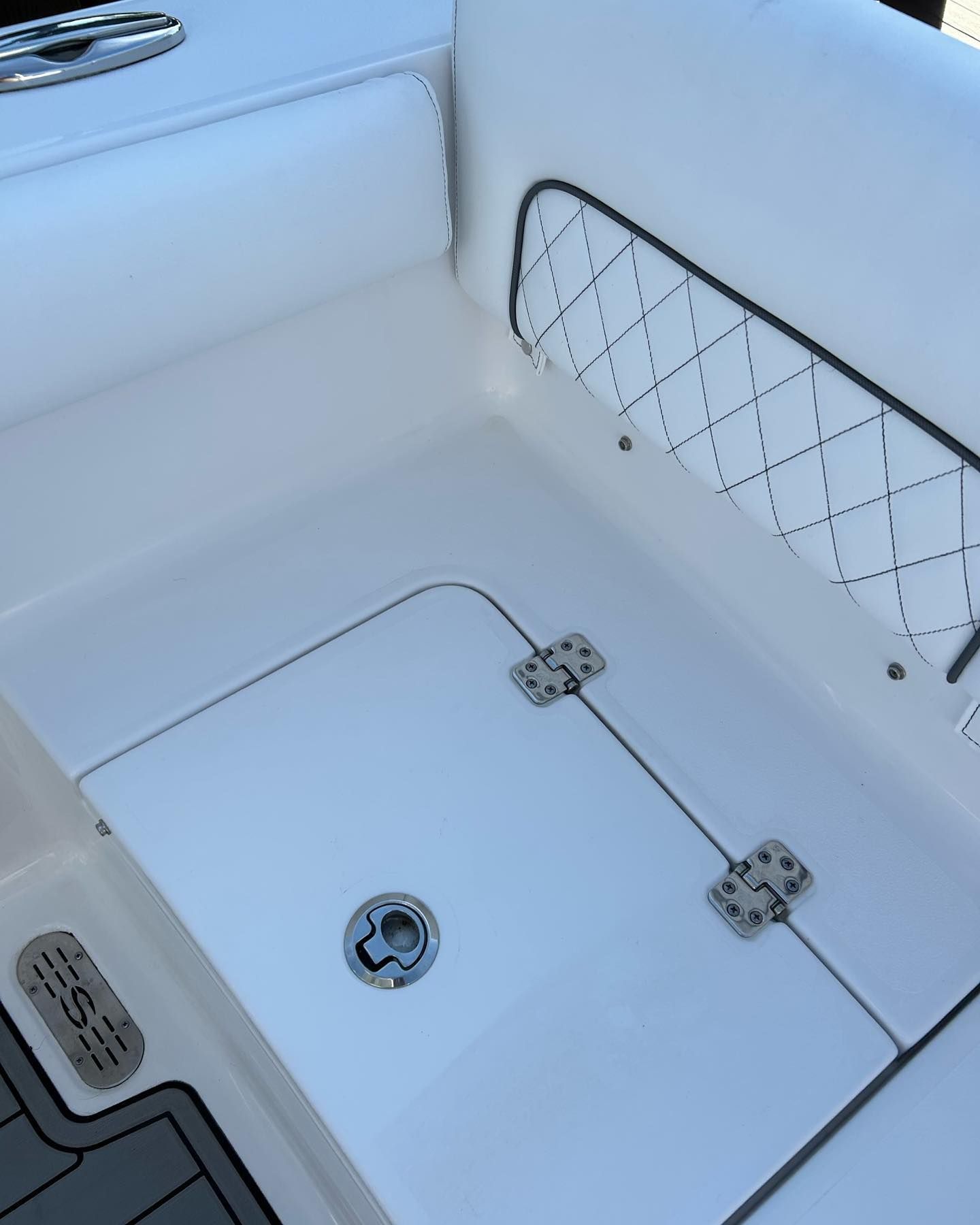 White boat interior with storage compartment, upholstered seat, and diamond-stitched panel.