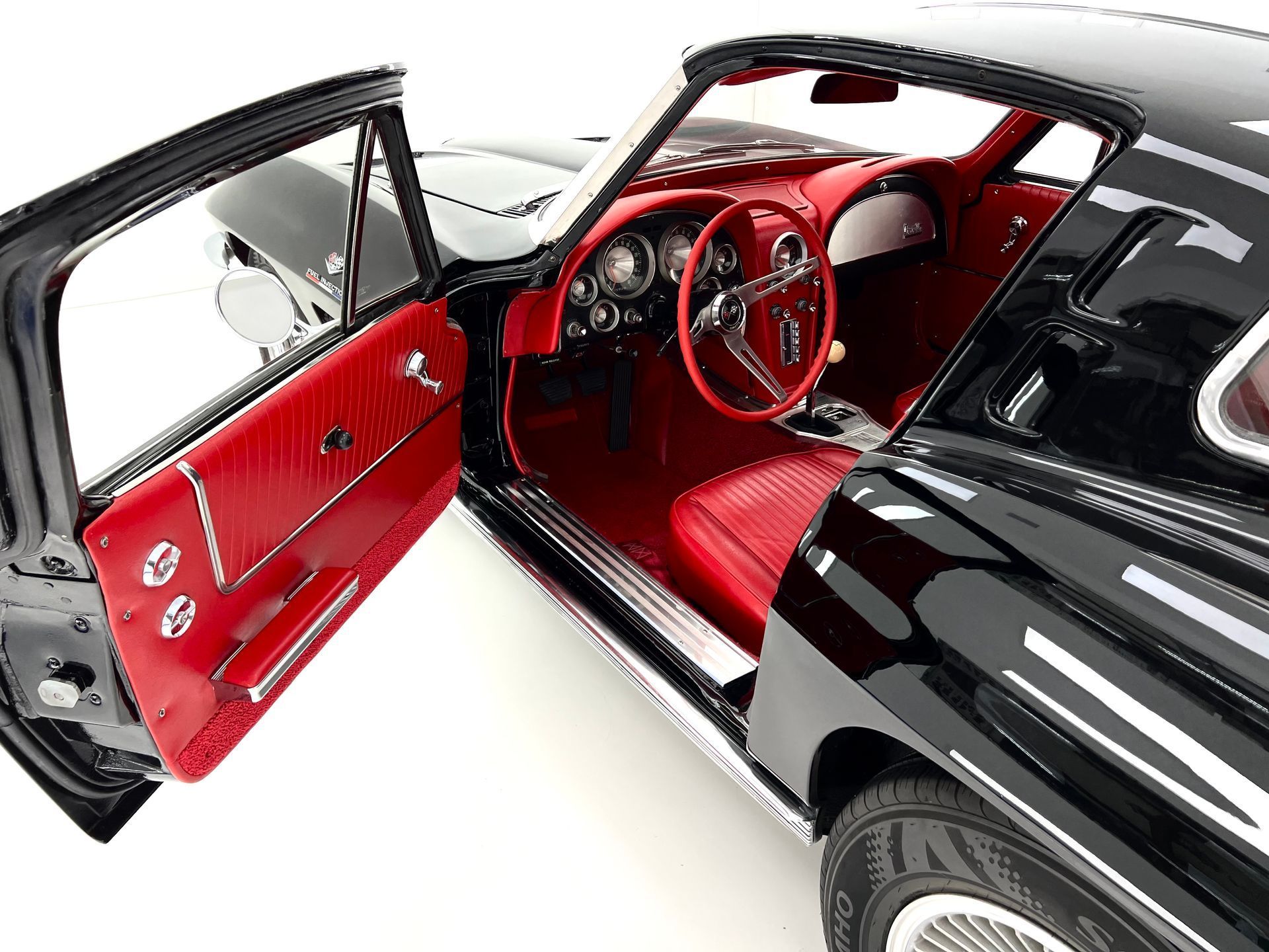 Black classic car with red interior, open door.