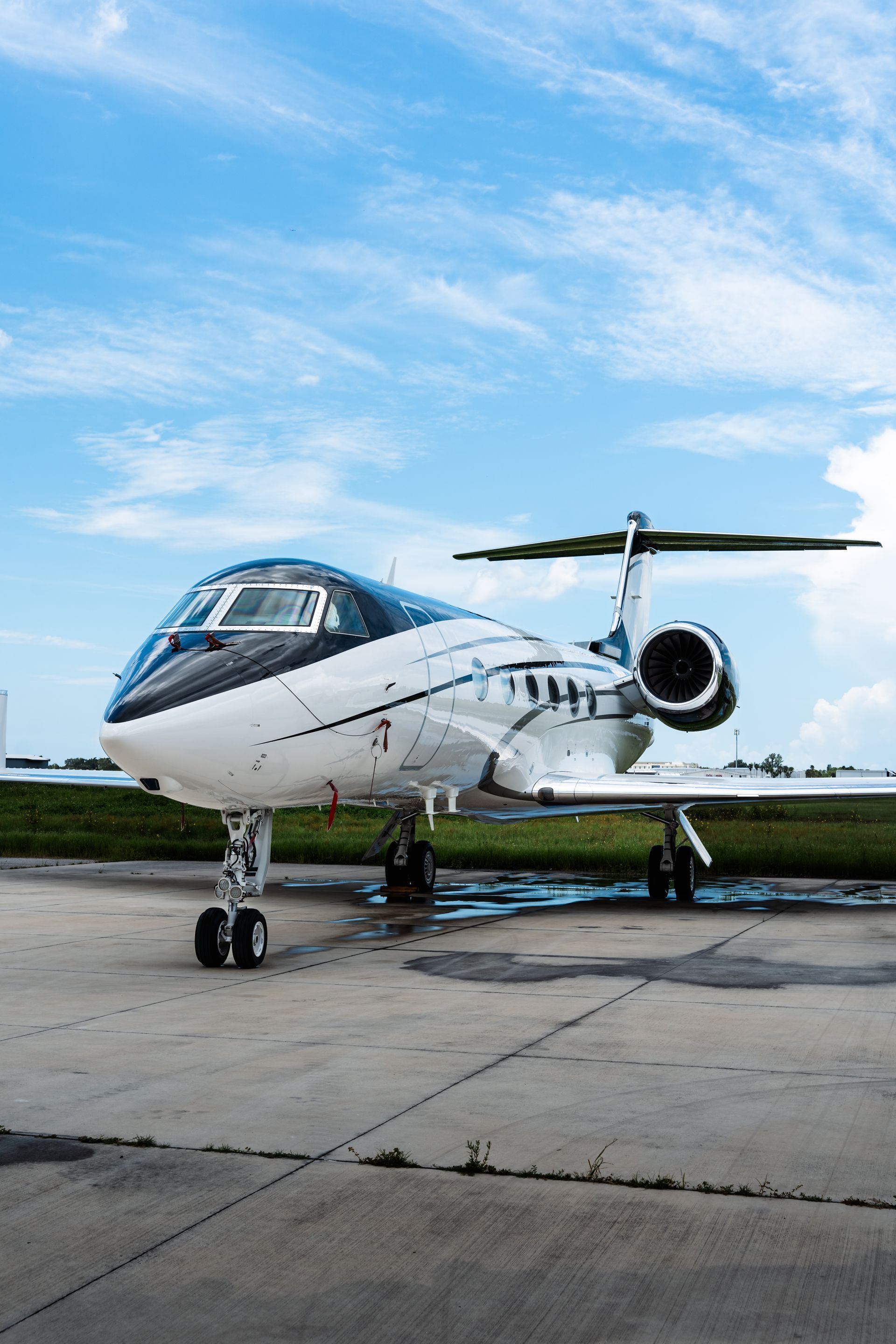 White and black private jet on a tarmac under a blue sky.