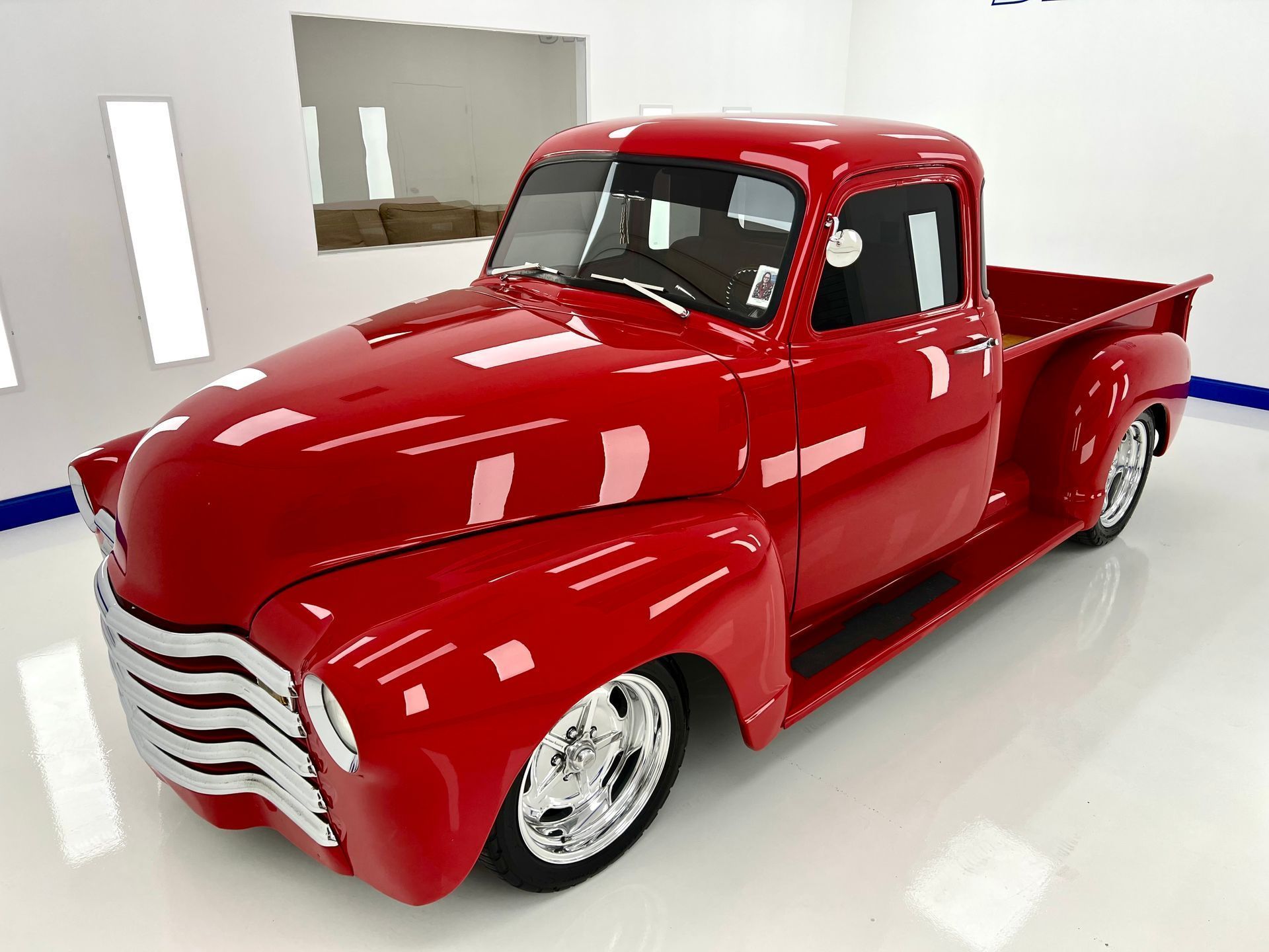 Red classic Chevrolet pickup truck in a bright showroom.