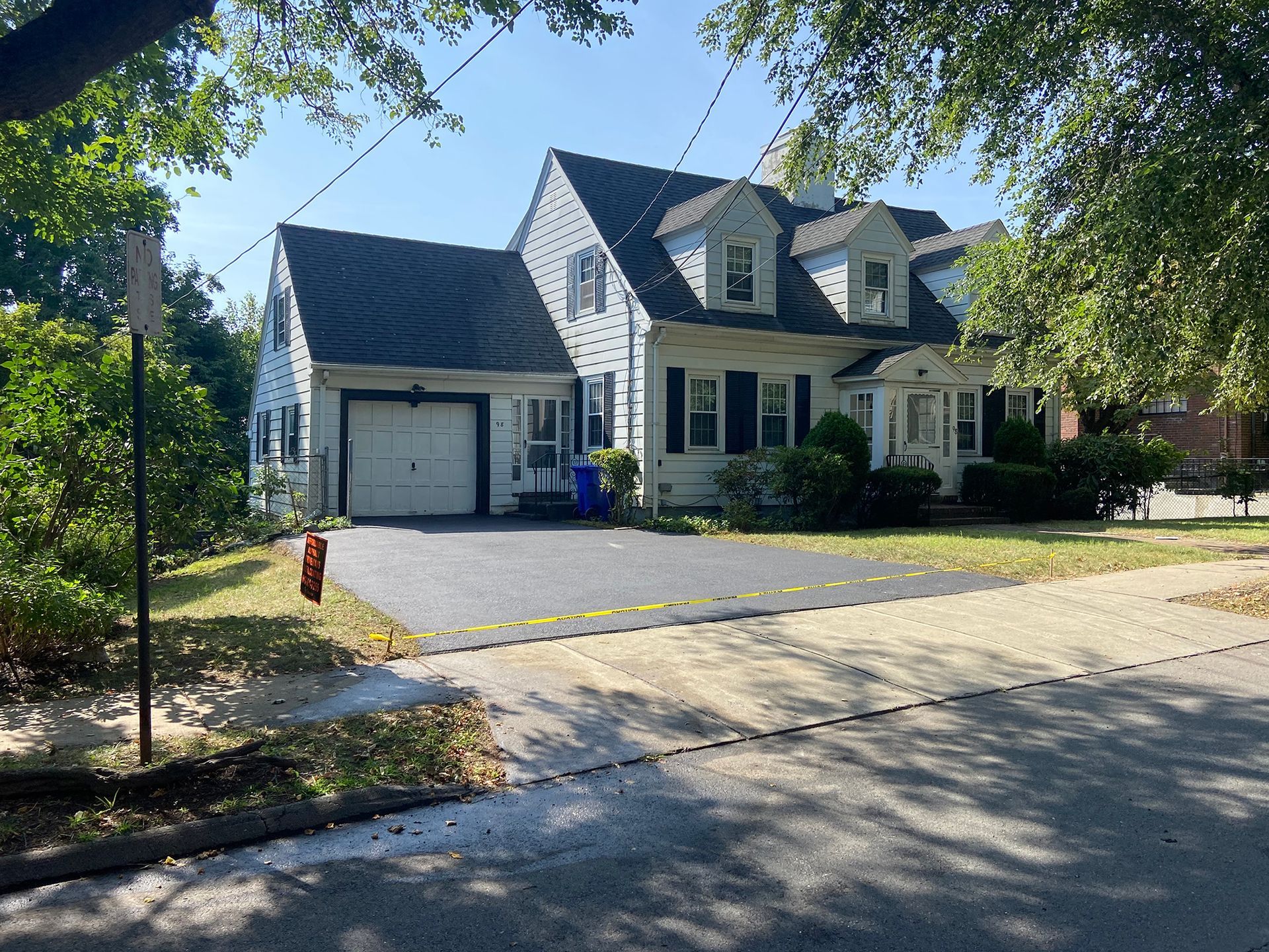 A two-story, white-sided house with a dark roof, attached garage, and asphalt driveway.