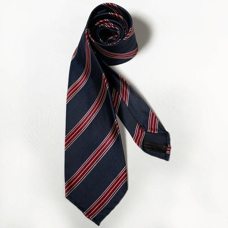 A blue and red striped tie is rolled up on a white surface