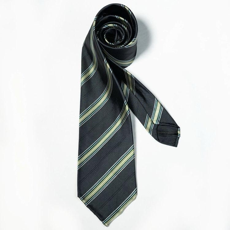 A black and gold striped tie is rolled up on a white background