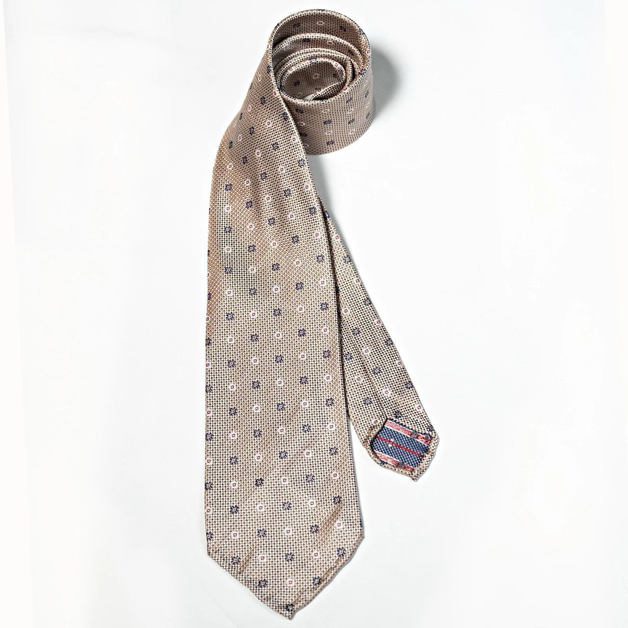 A tie with a pattern on it is rolled up on a white surface