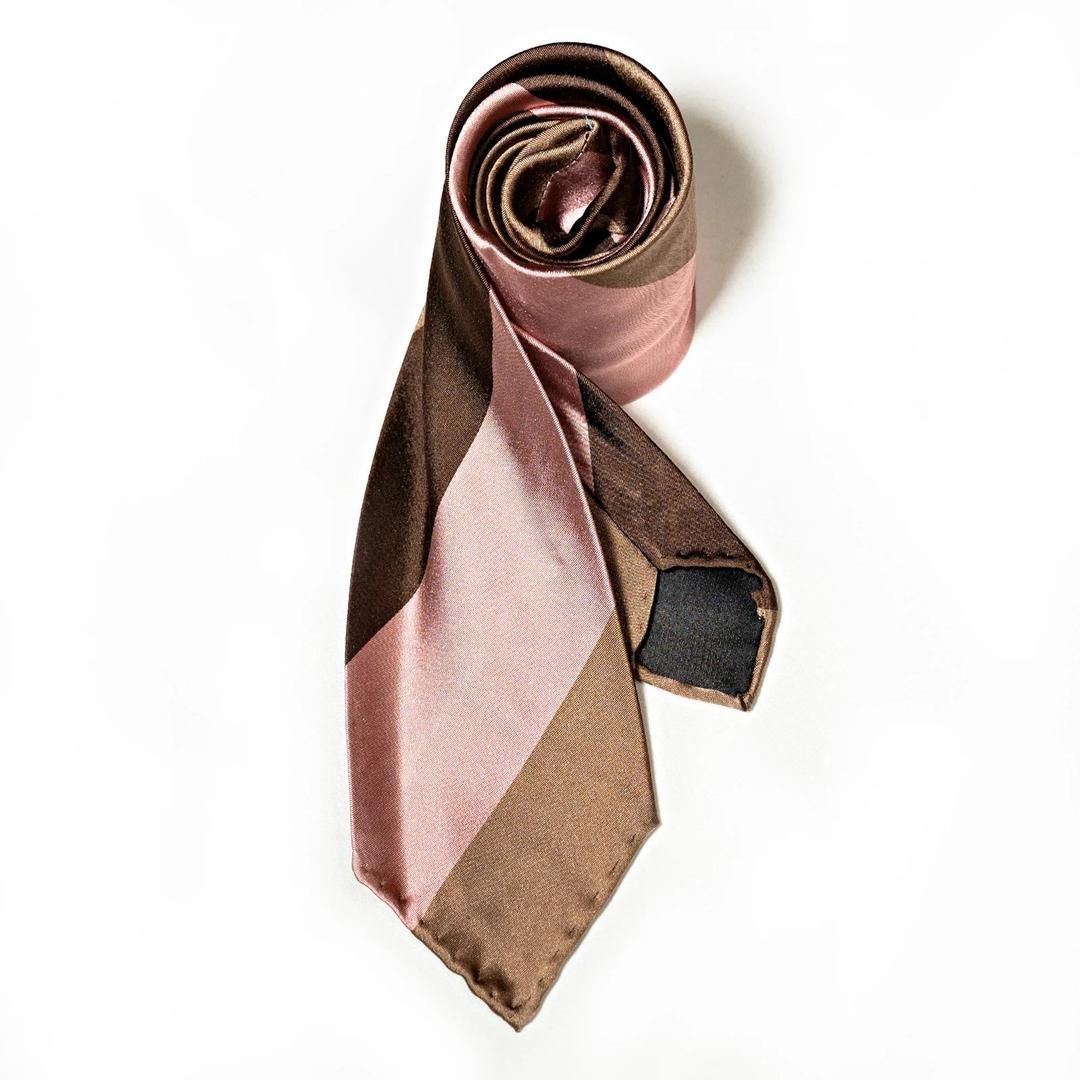 A brown and pink tie is rolled up on a white surface