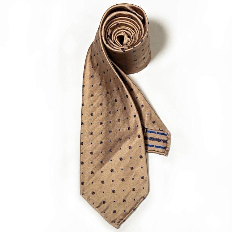 A tan tie with black polka dots on it