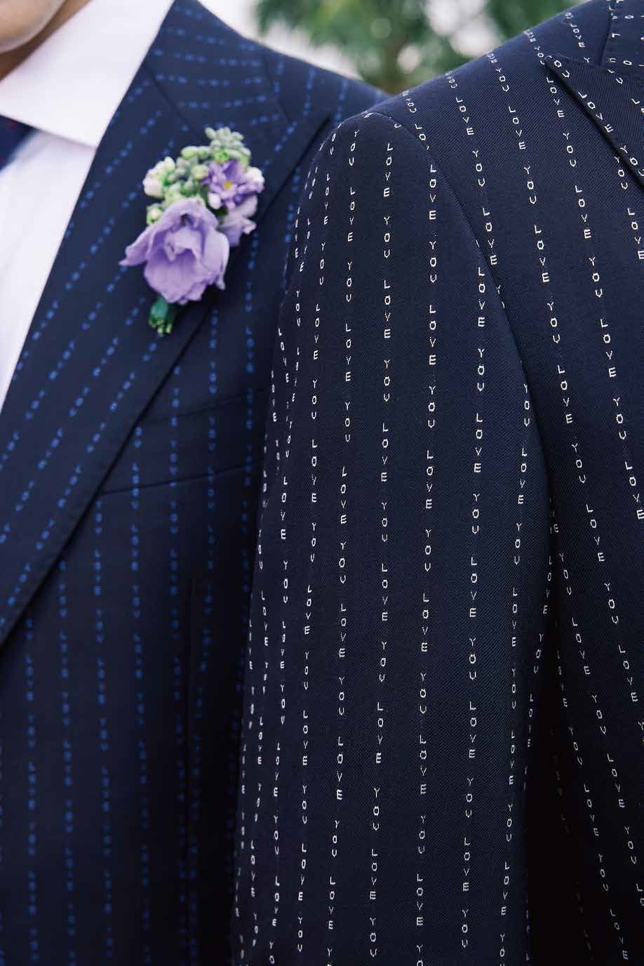 A man in a blue suit has a purple flower pinned to his jacket