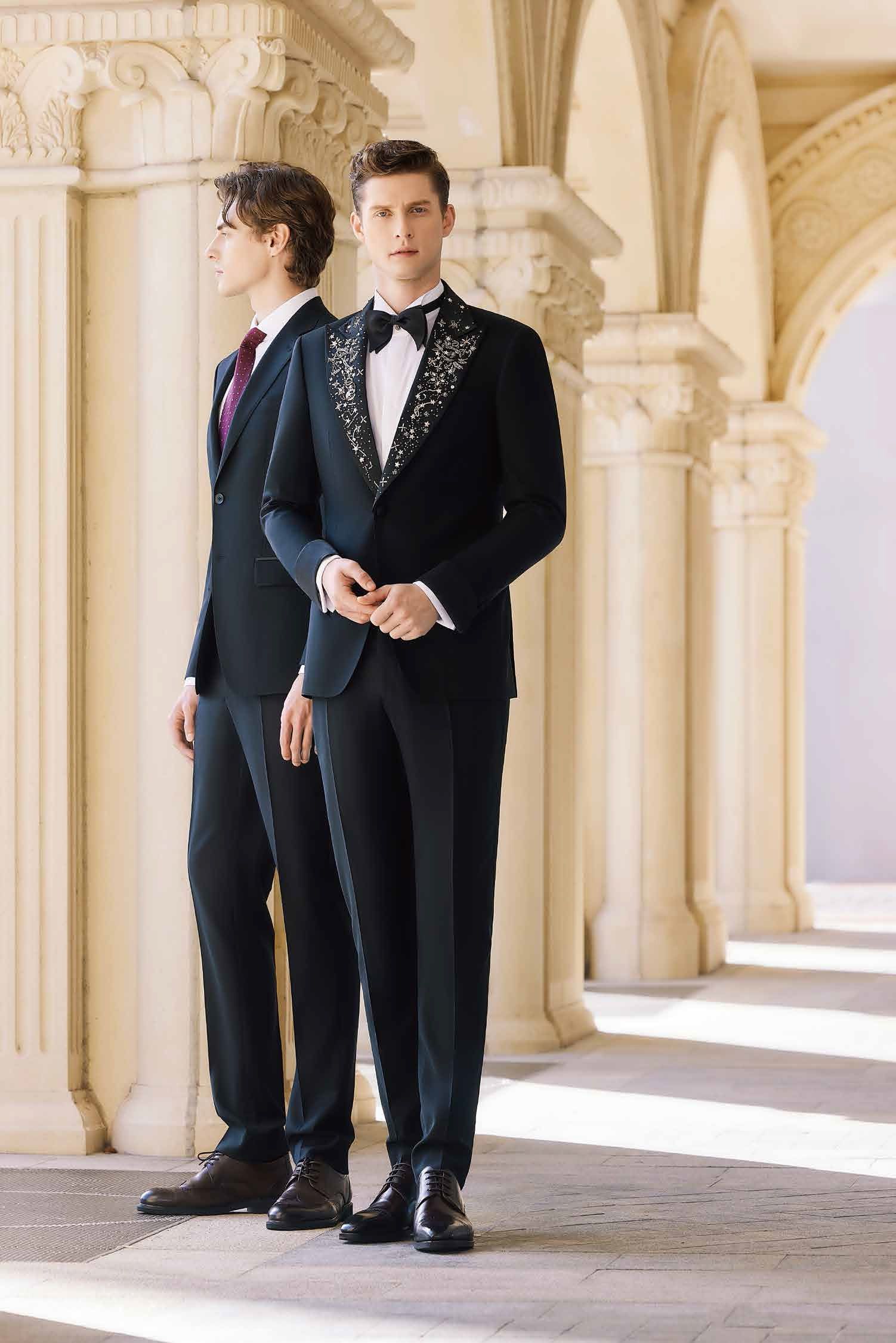 Two men in tuxedos are standing next to each other in a hallway.