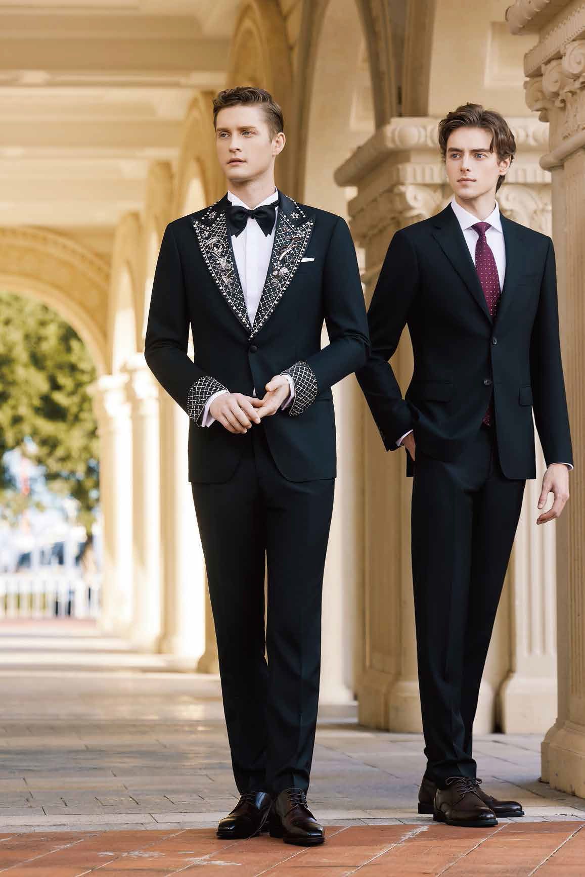 Two men in tuxedos are standing next to each other holding hands.