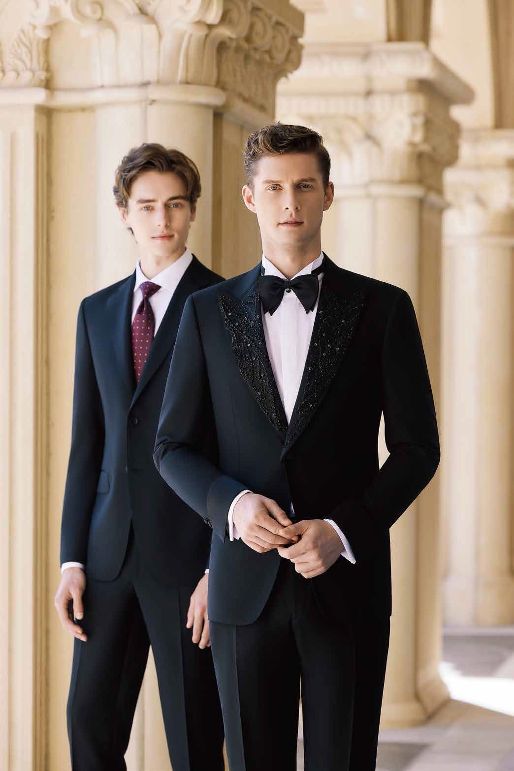 Two men in tuxedos and ties are standing next to each other.