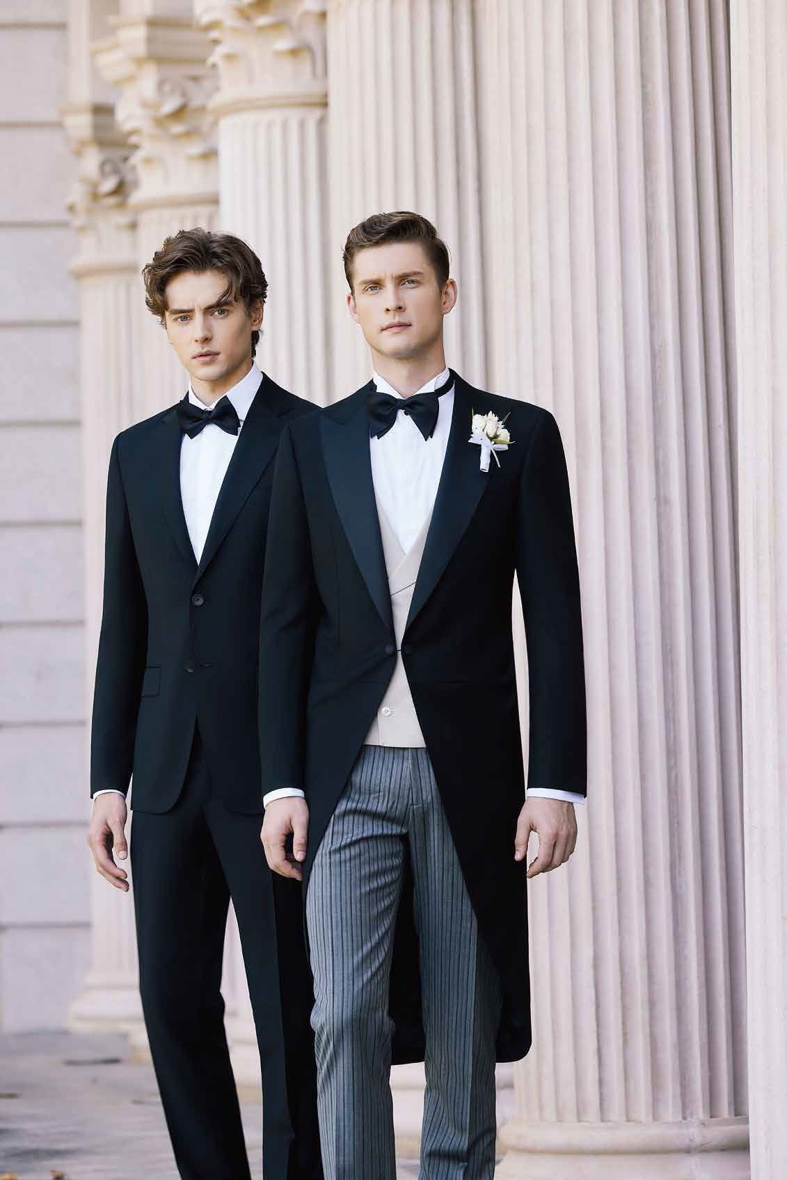 Two men in tuxedos are standing next to each other in front of a building.