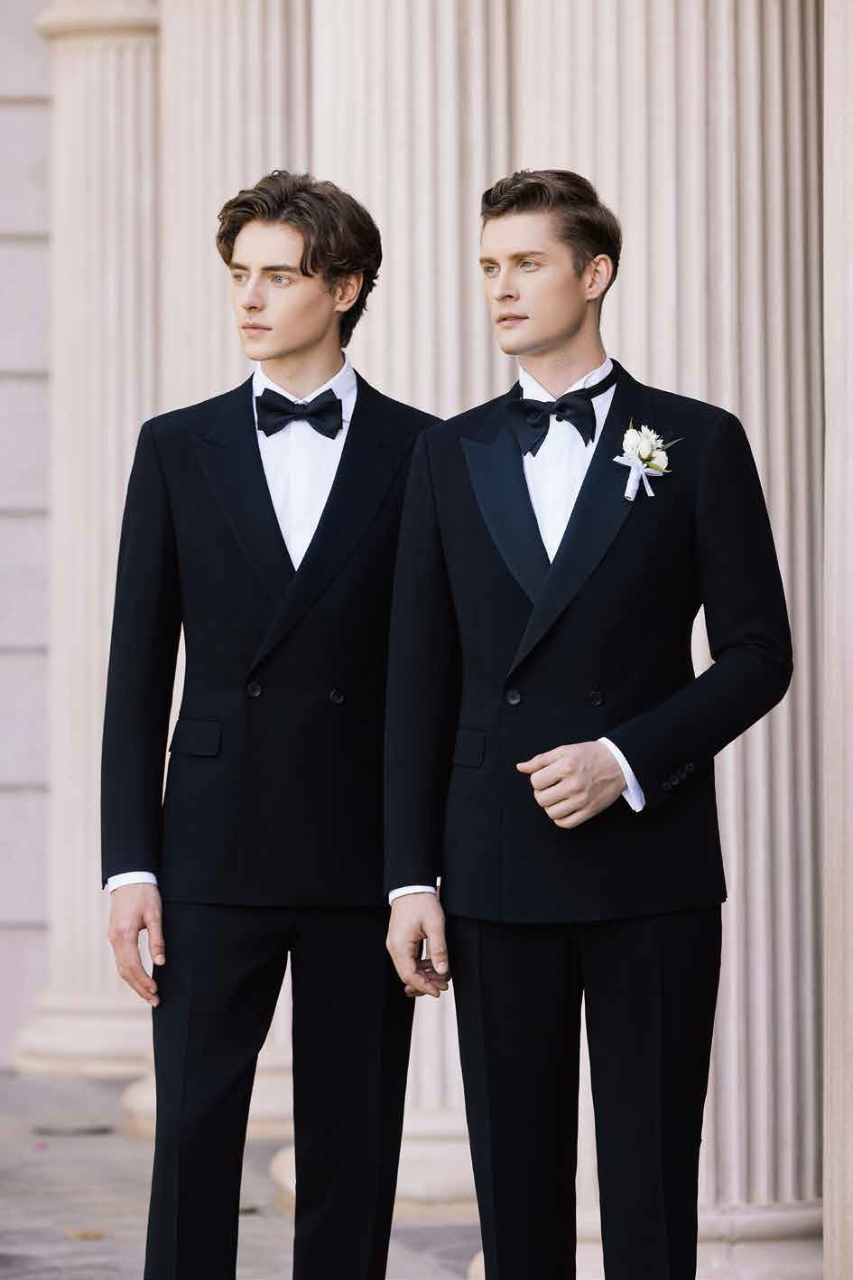 Two men in tuxedos are standing next to each other in front of a building.