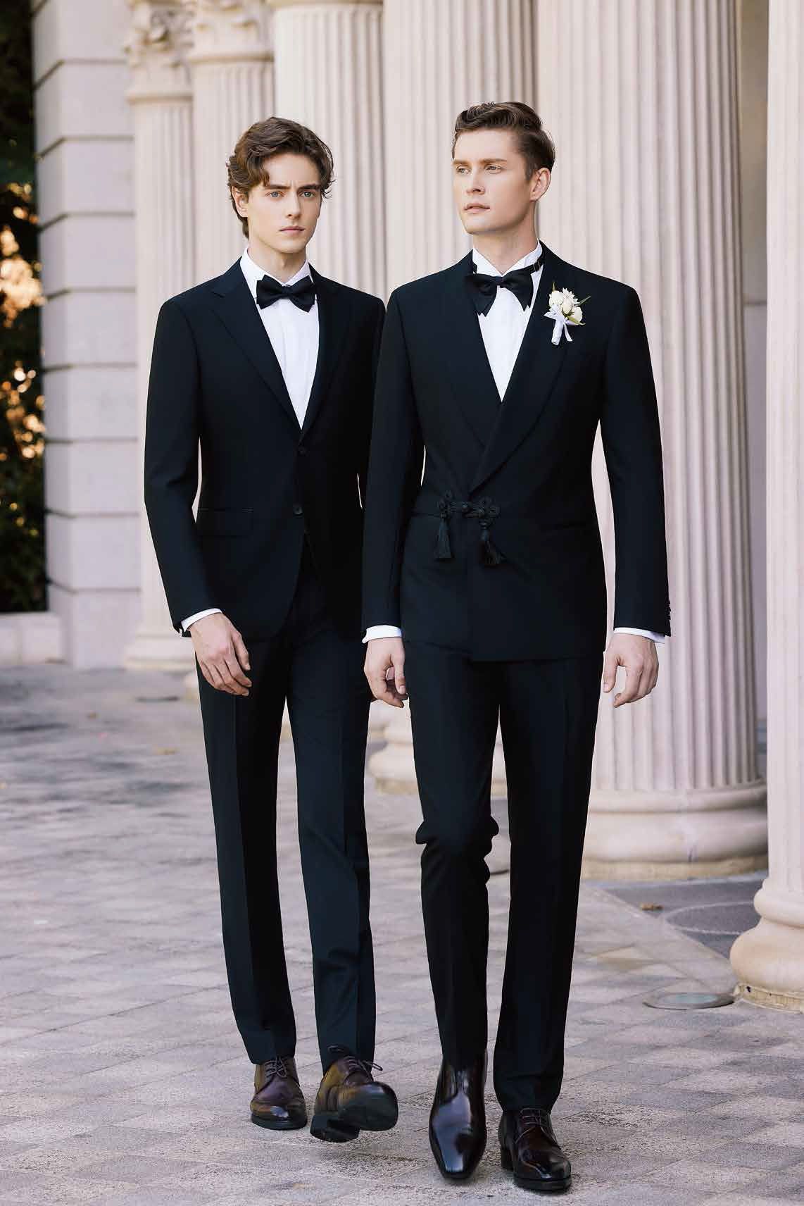 Two men in tuxedos and bow ties are walking down a sidewalk.