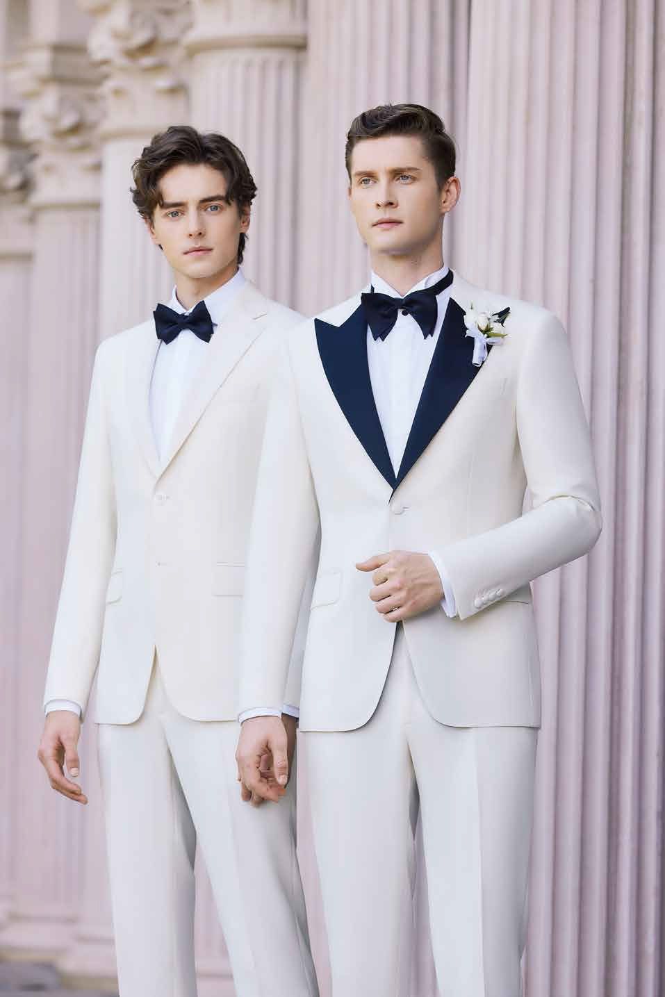 Two men in white suits and bow ties are standing next to each other.