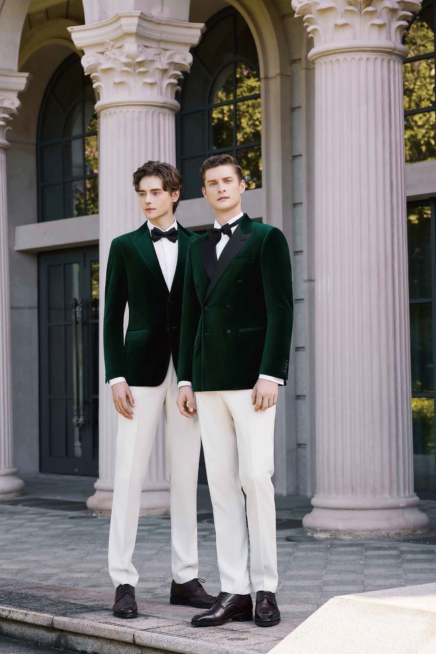 Two men in green suits and white pants are standing next to each other in front of a building.