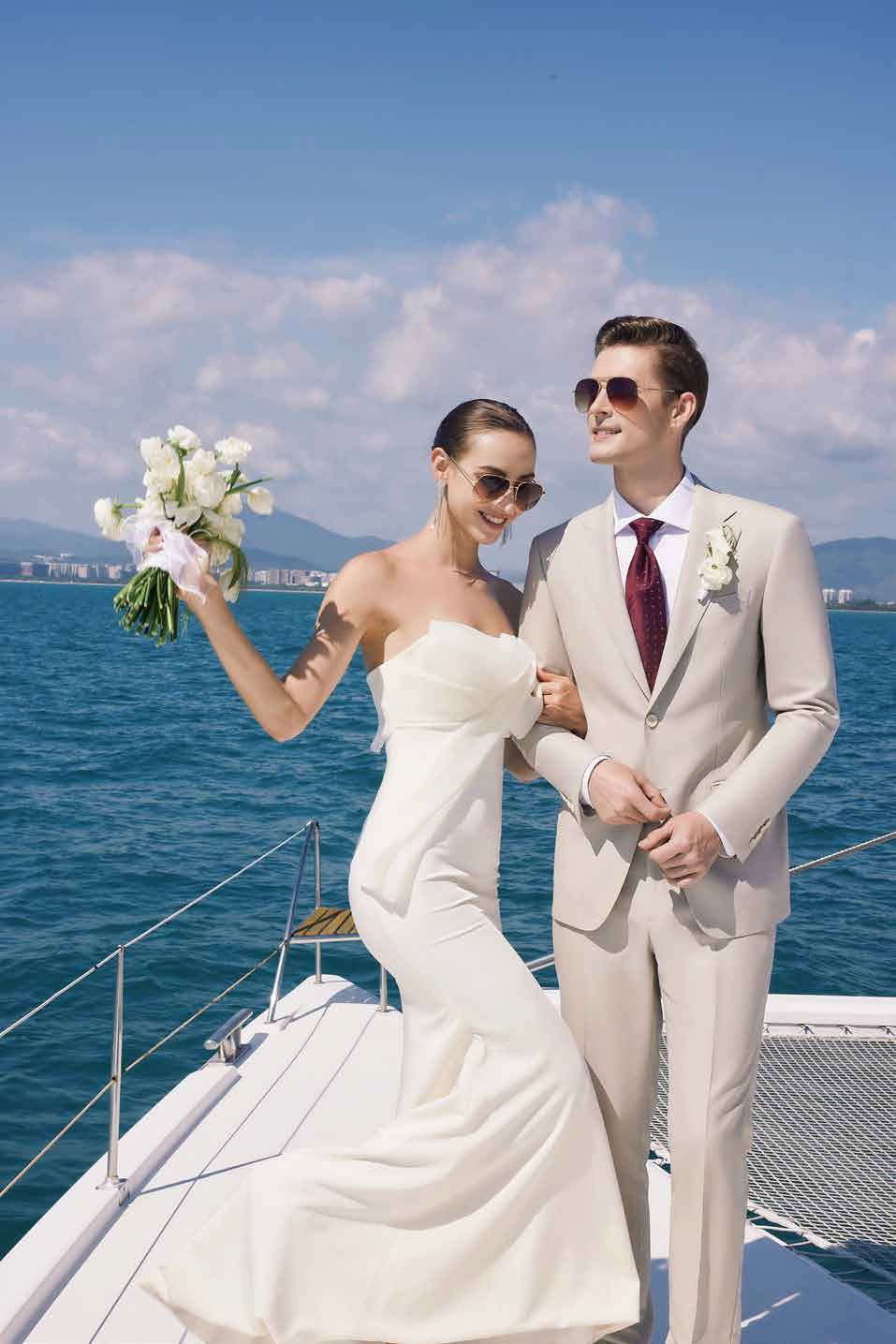 A bride and groom are standing on a boat in the ocean.