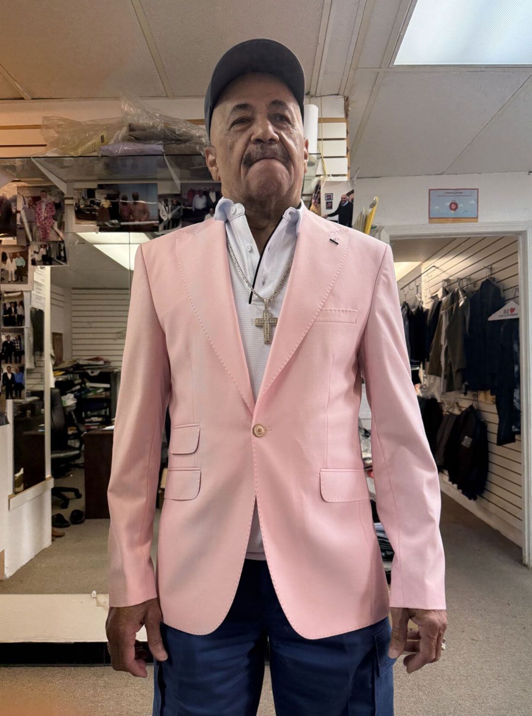 A man wearing a pink jacket and hat is standing in a store.