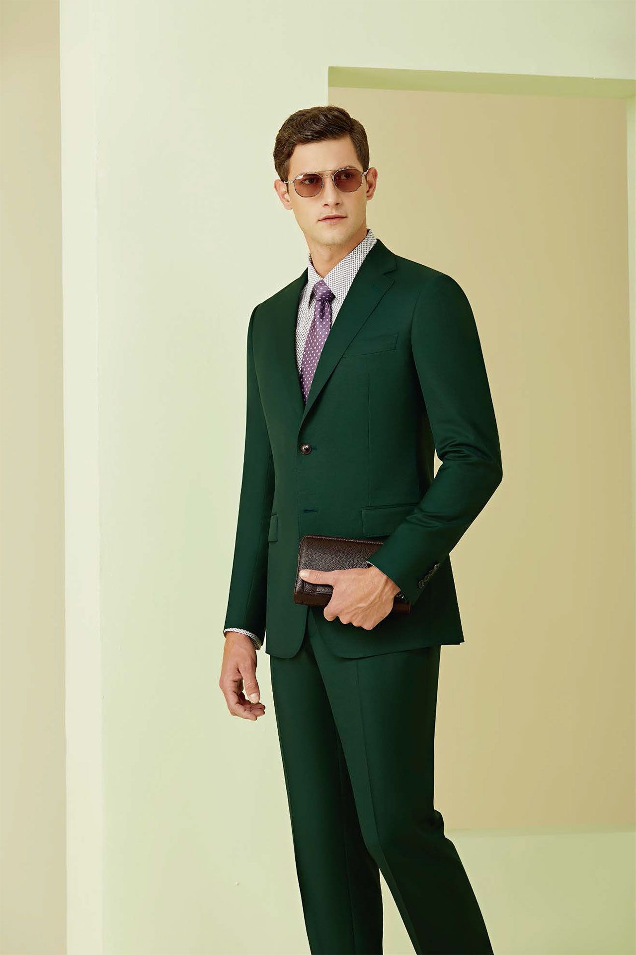 A man in a green suit and tie is standing in a room