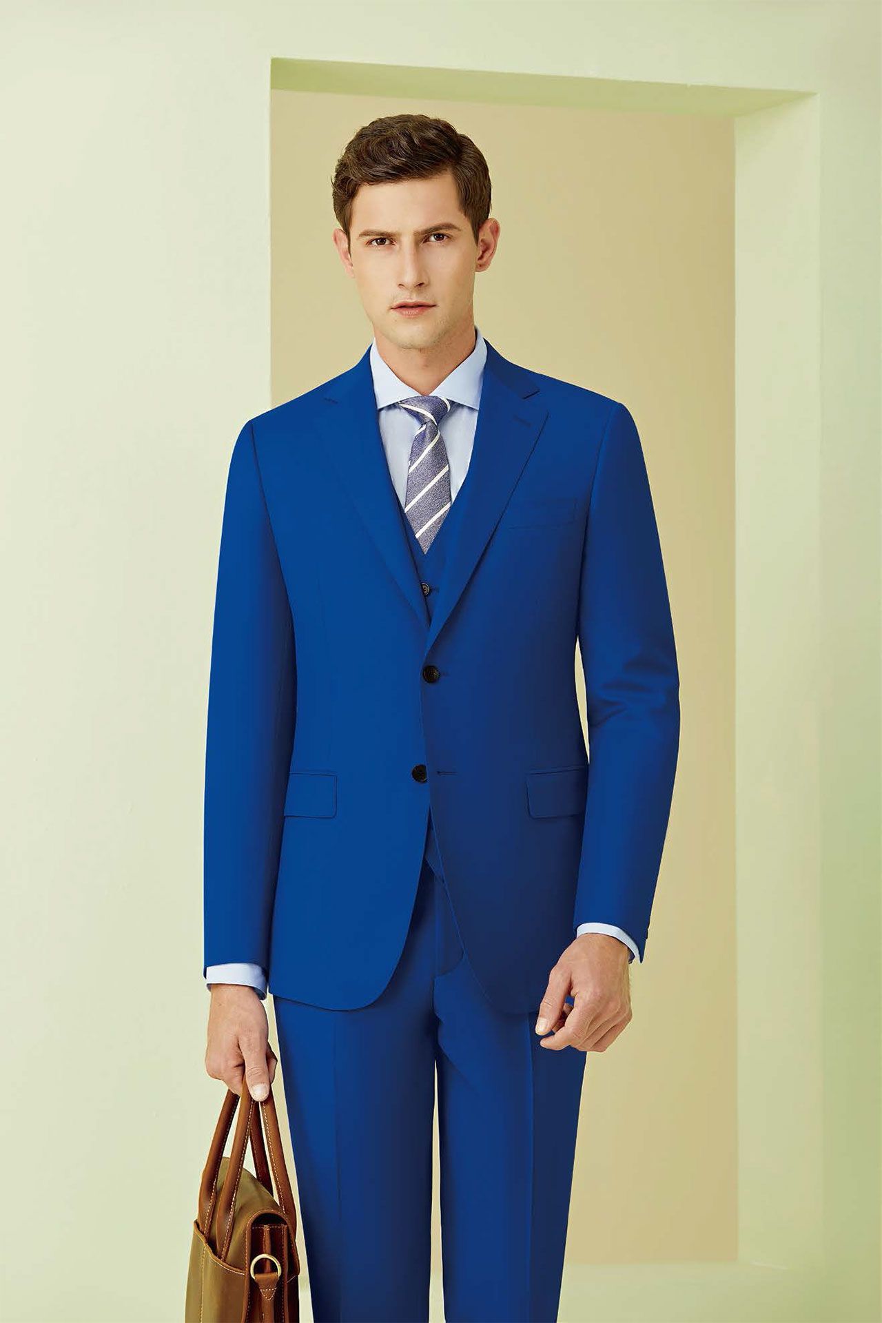 A man in a blue suit and tie is holding a briefcase