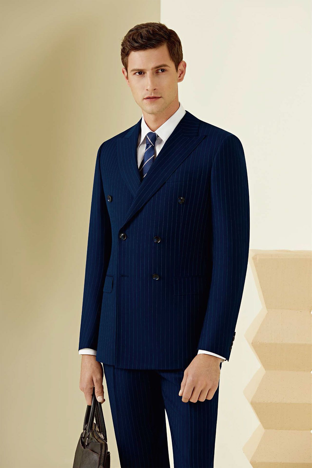 A man in a blue suit and tie is holding a briefcase