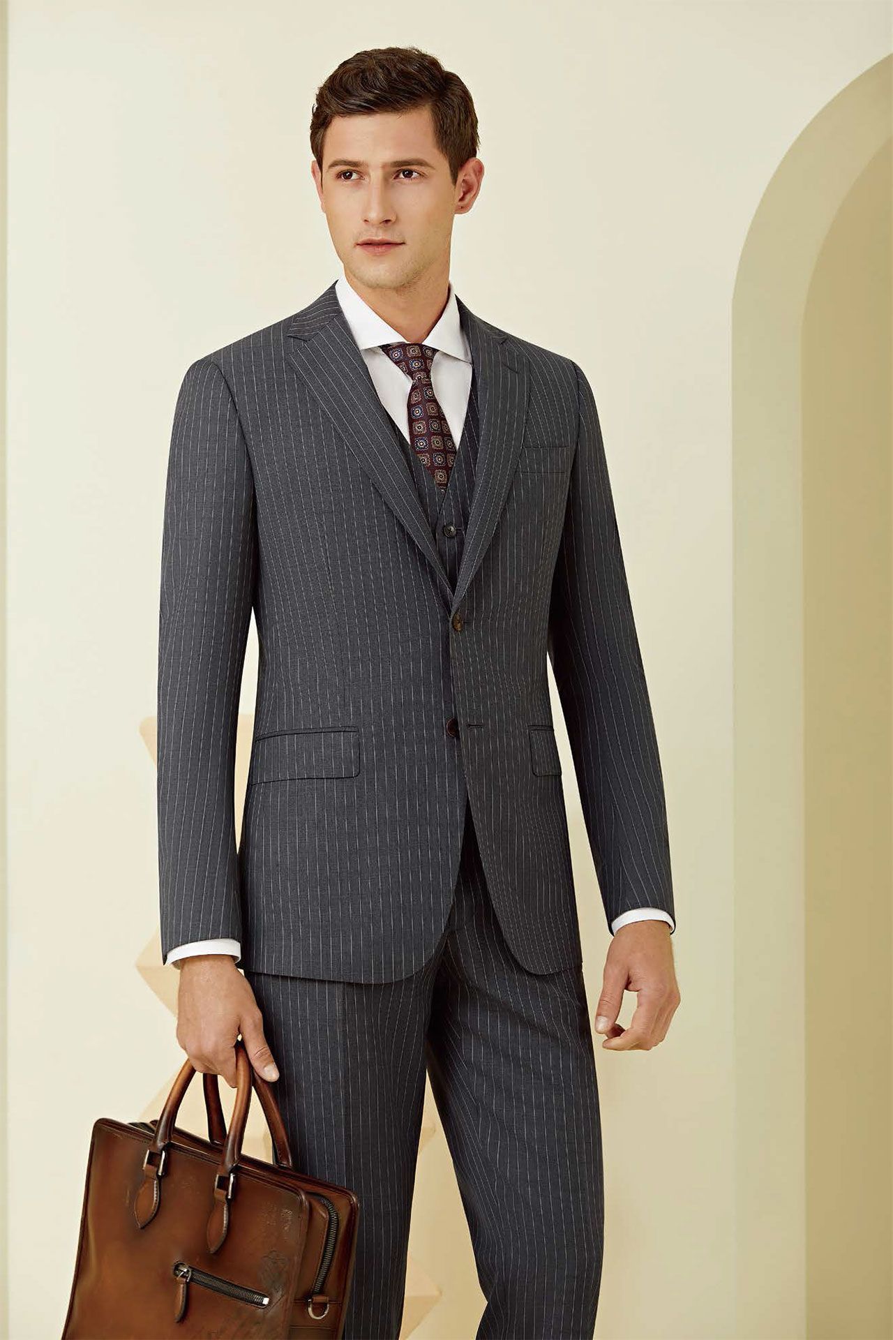 A man in a suit and tie is holding a brown briefcase