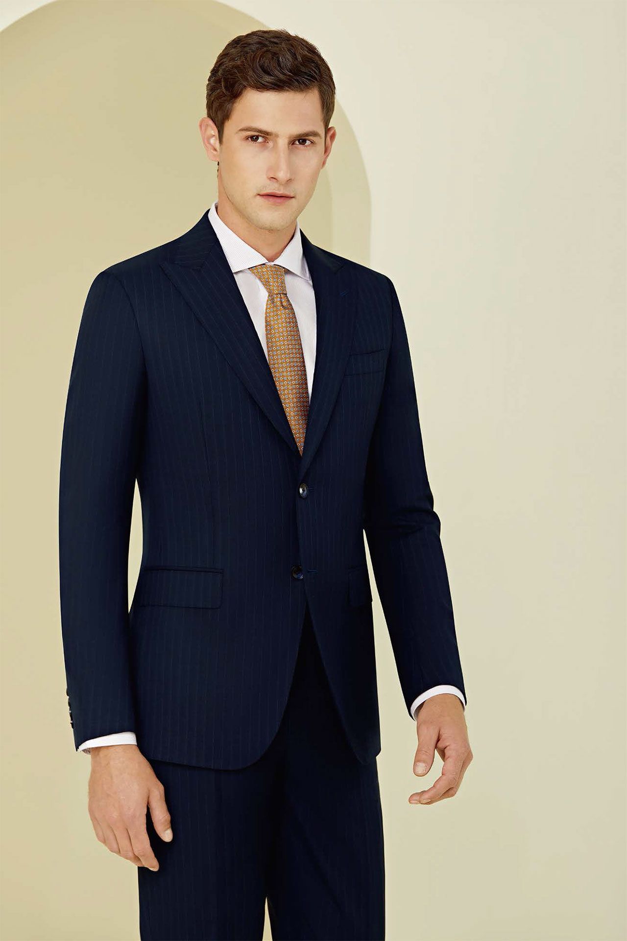 A man in a suit and tie is standing in front of a wall