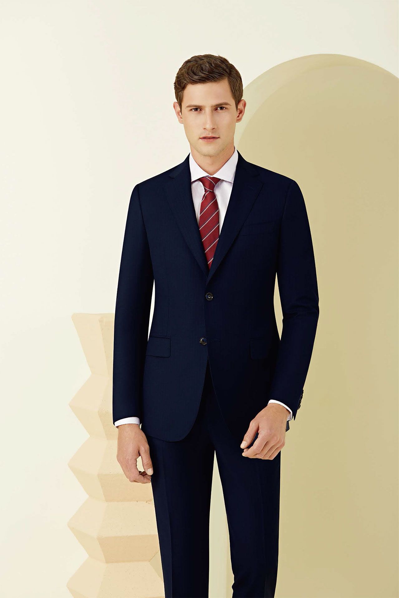 A man in a suit and tie is standing in front of a wall