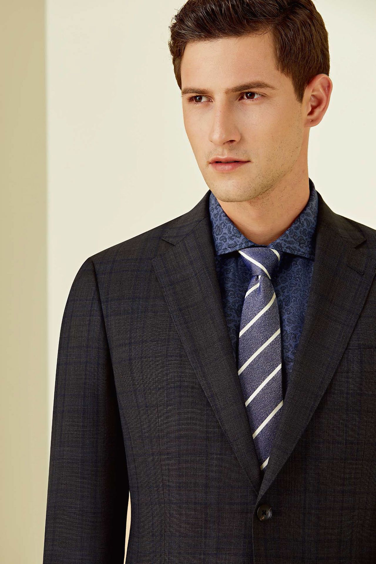 A man in a suit and tie is standing next to a wall