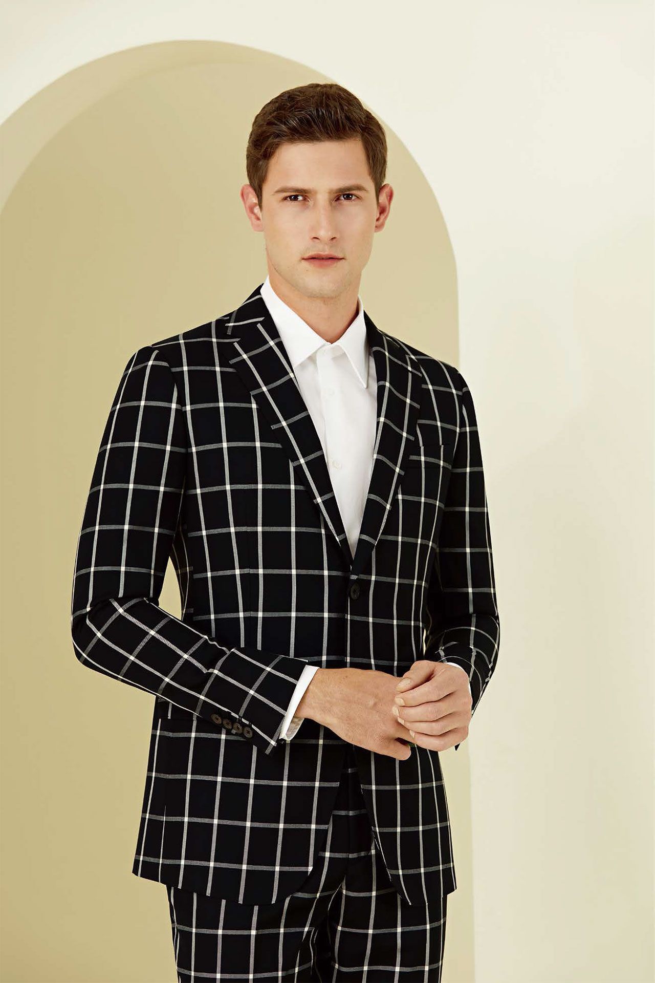 A man is wearing a black and white plaid suit and a white shirt