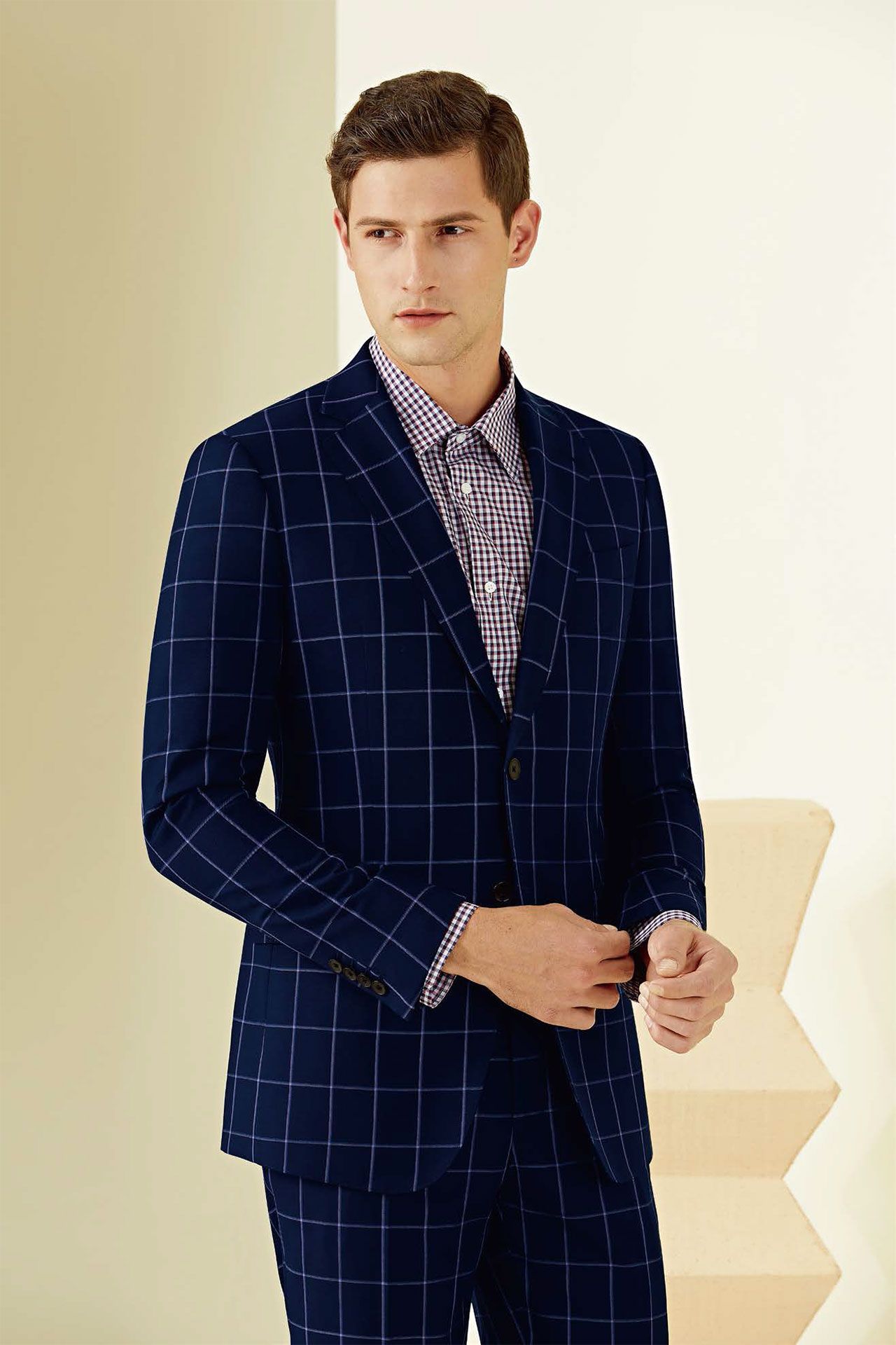 A man is wearing a blue plaid suit and a striped shirt