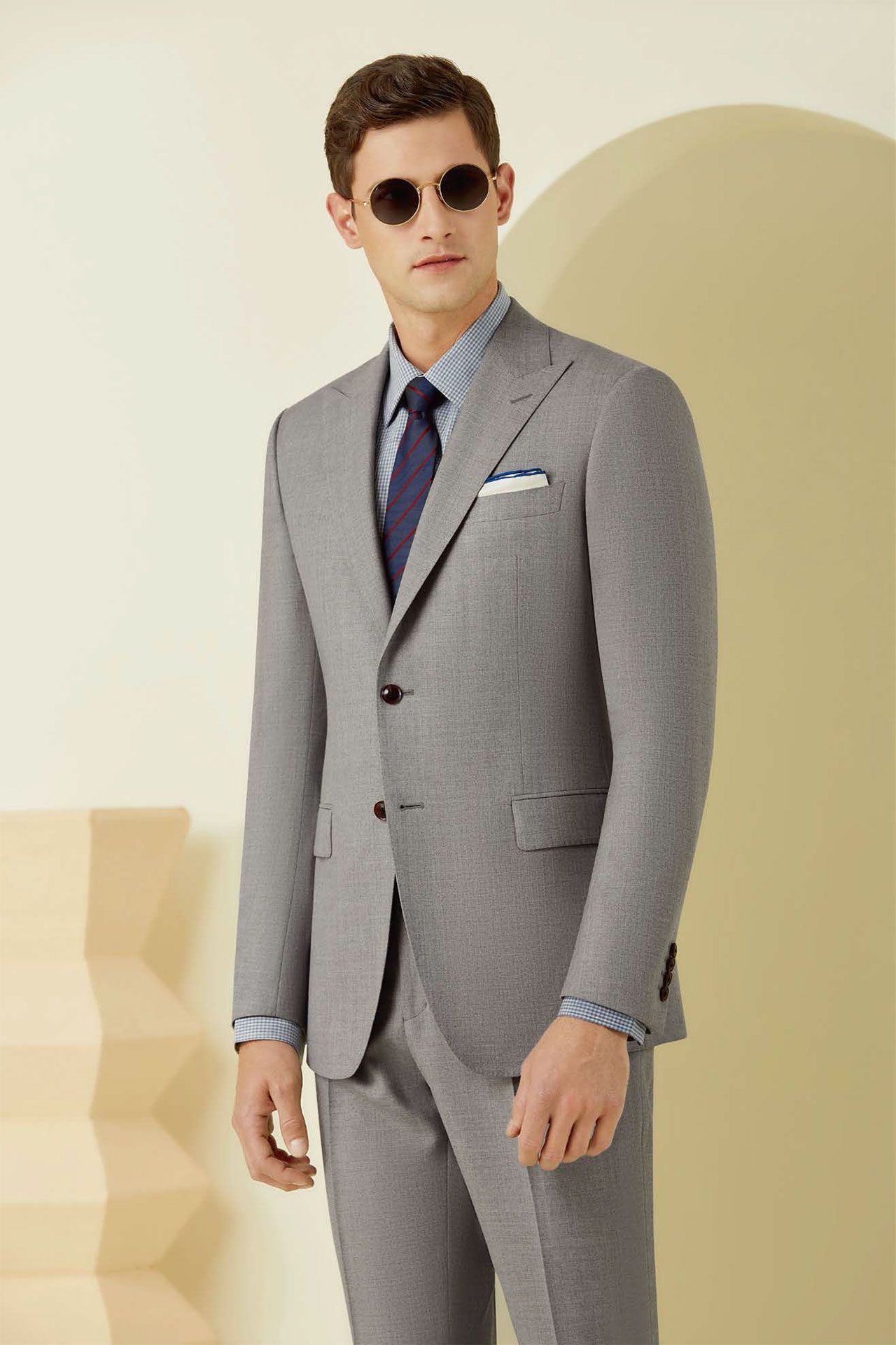 A man is wearing a grey suit and sunglasses