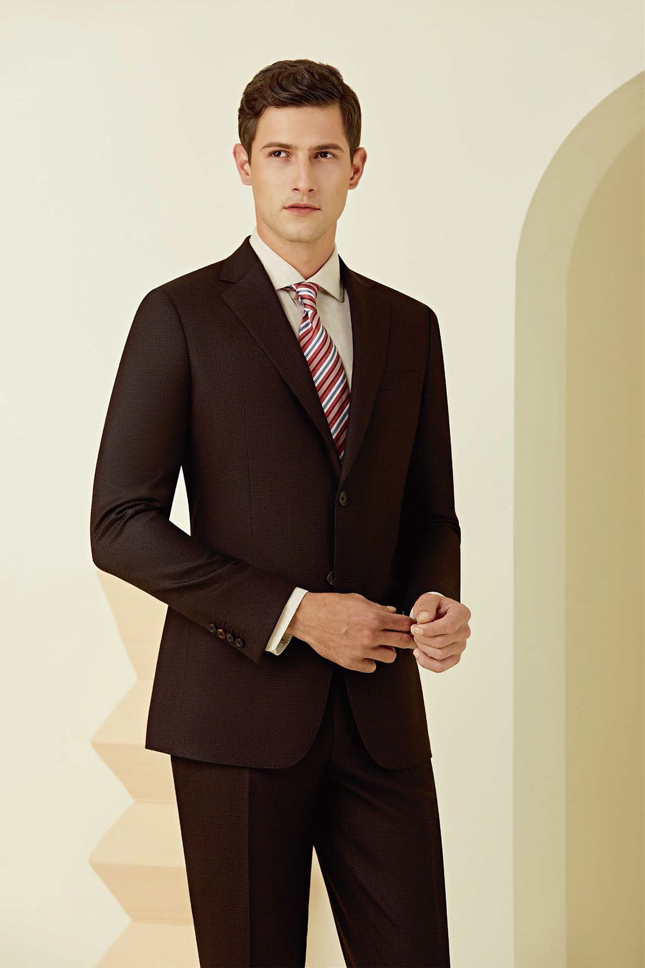 A man is wearing a brown suit and tie
