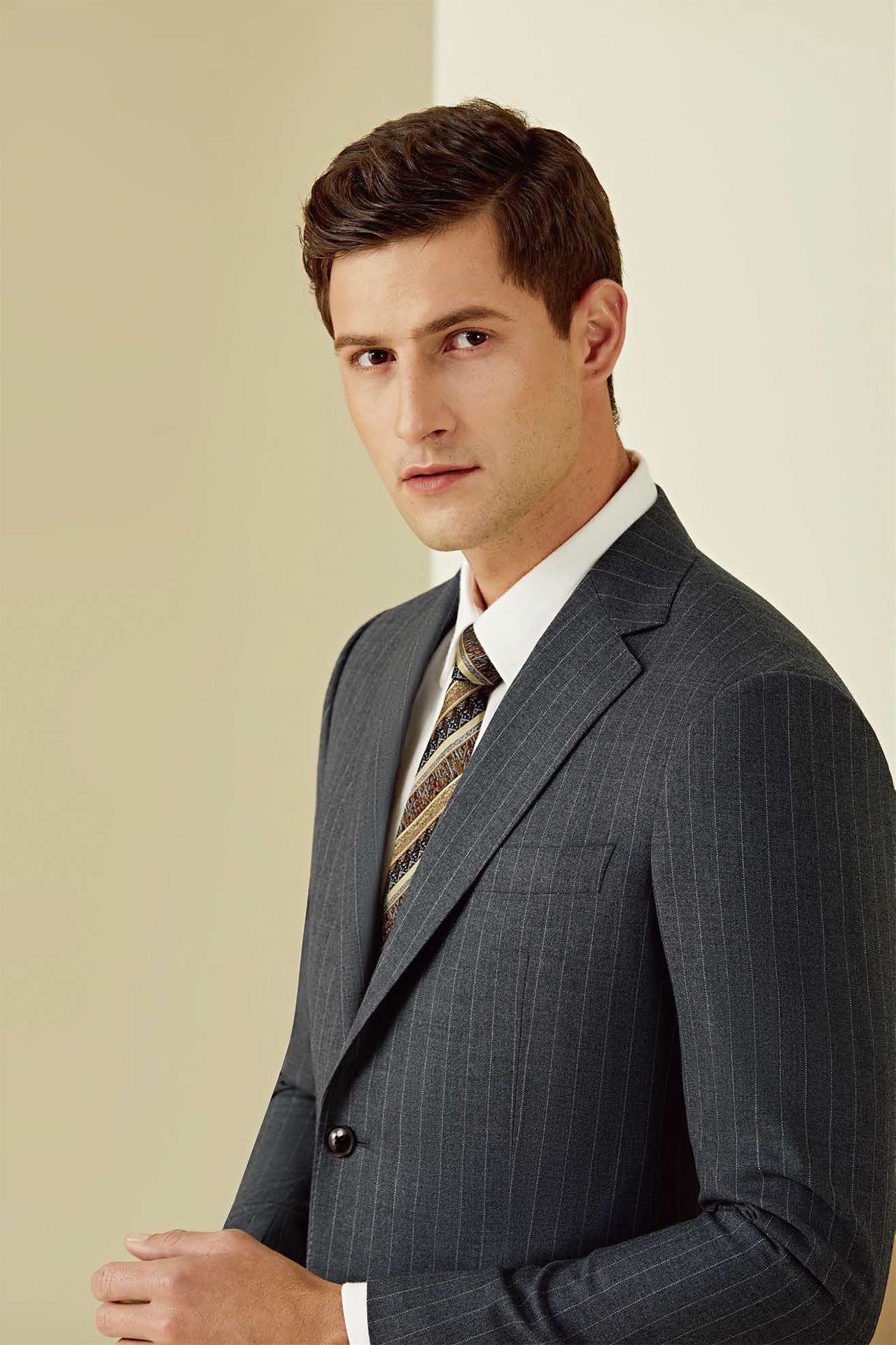 A man in a suit and tie is standing in front of a wall