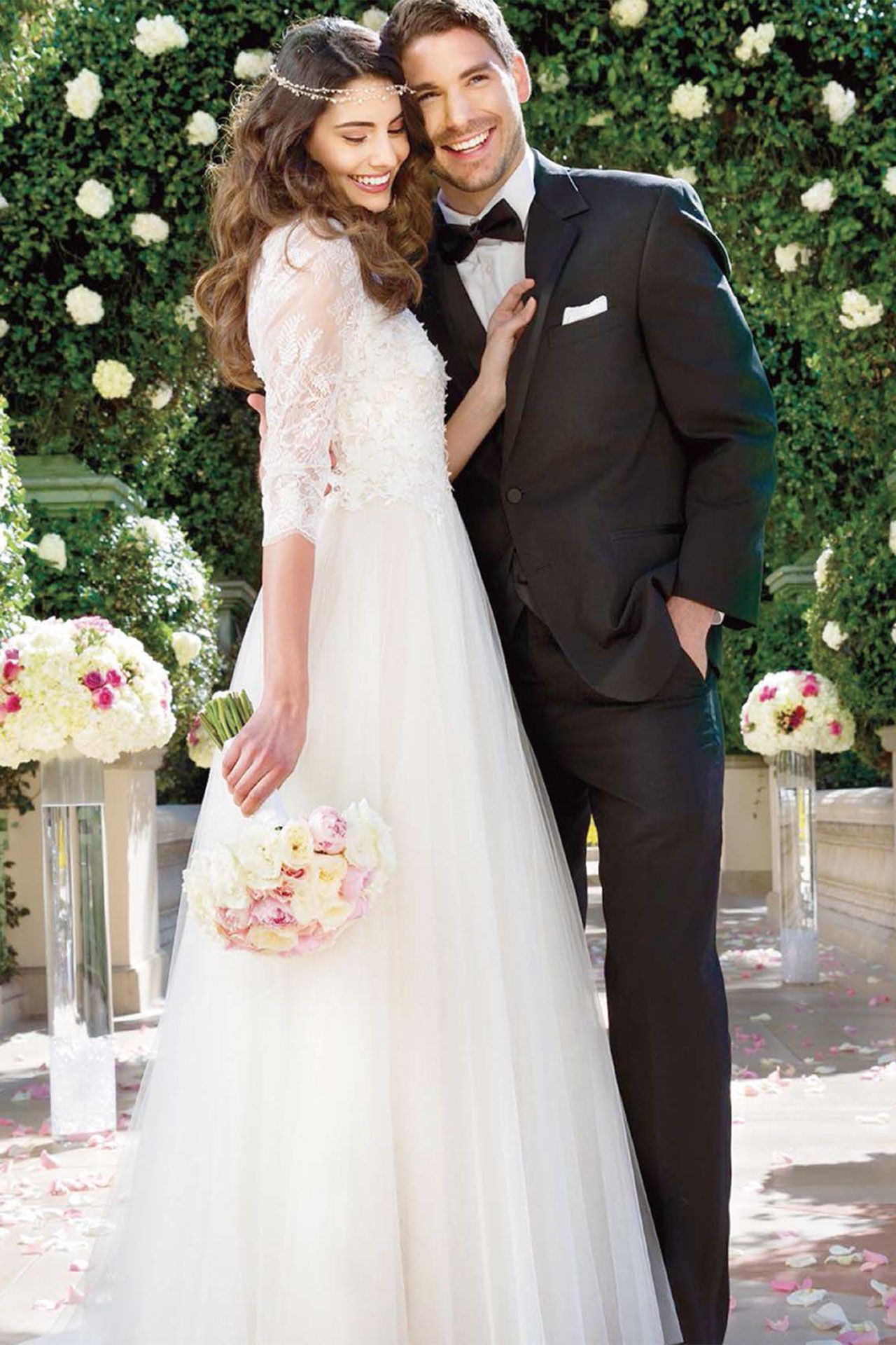 A bride and groom are posing for a picture while the bride is holding a bouquet of flowers