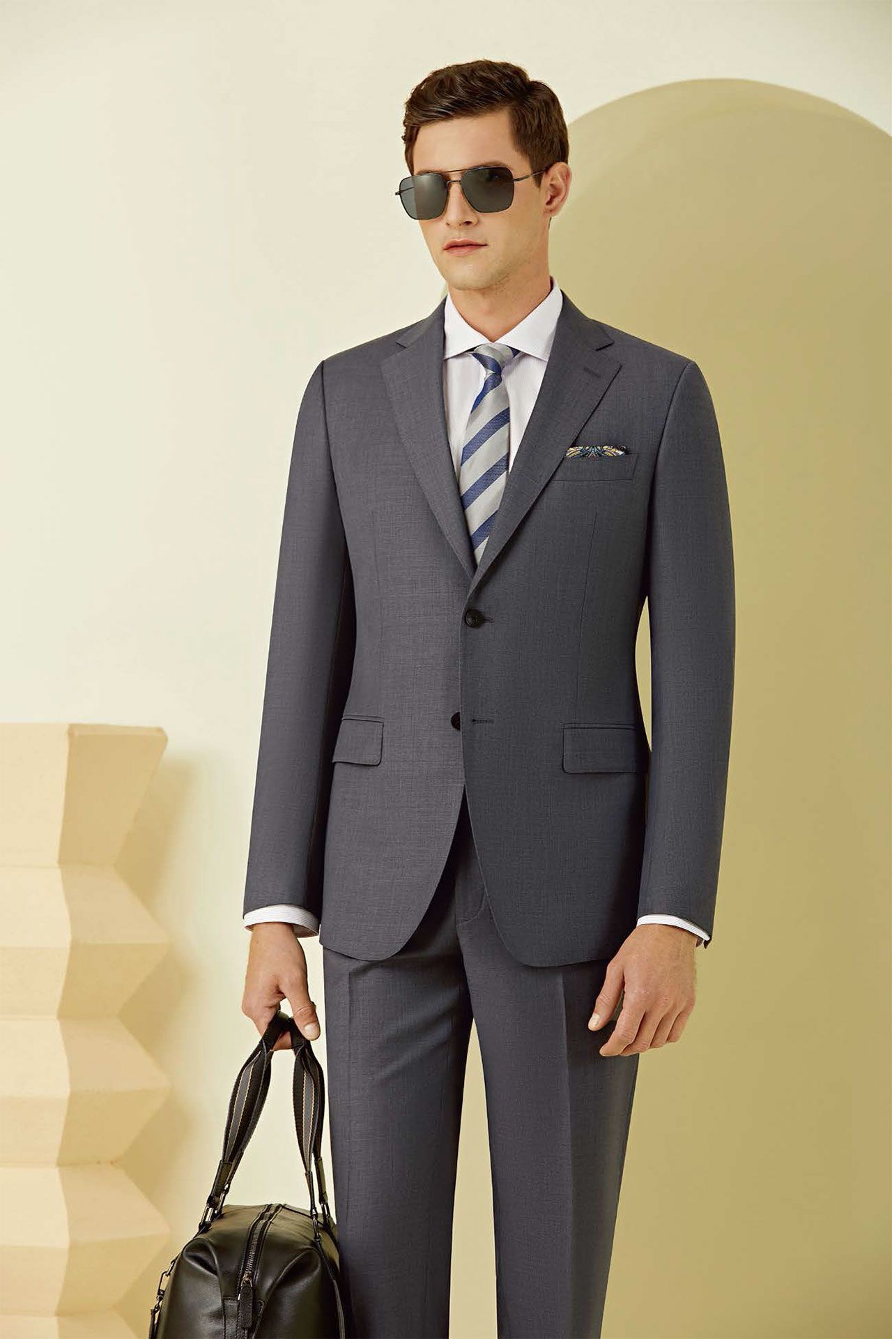 A man in a suit and tie is holding a black bag