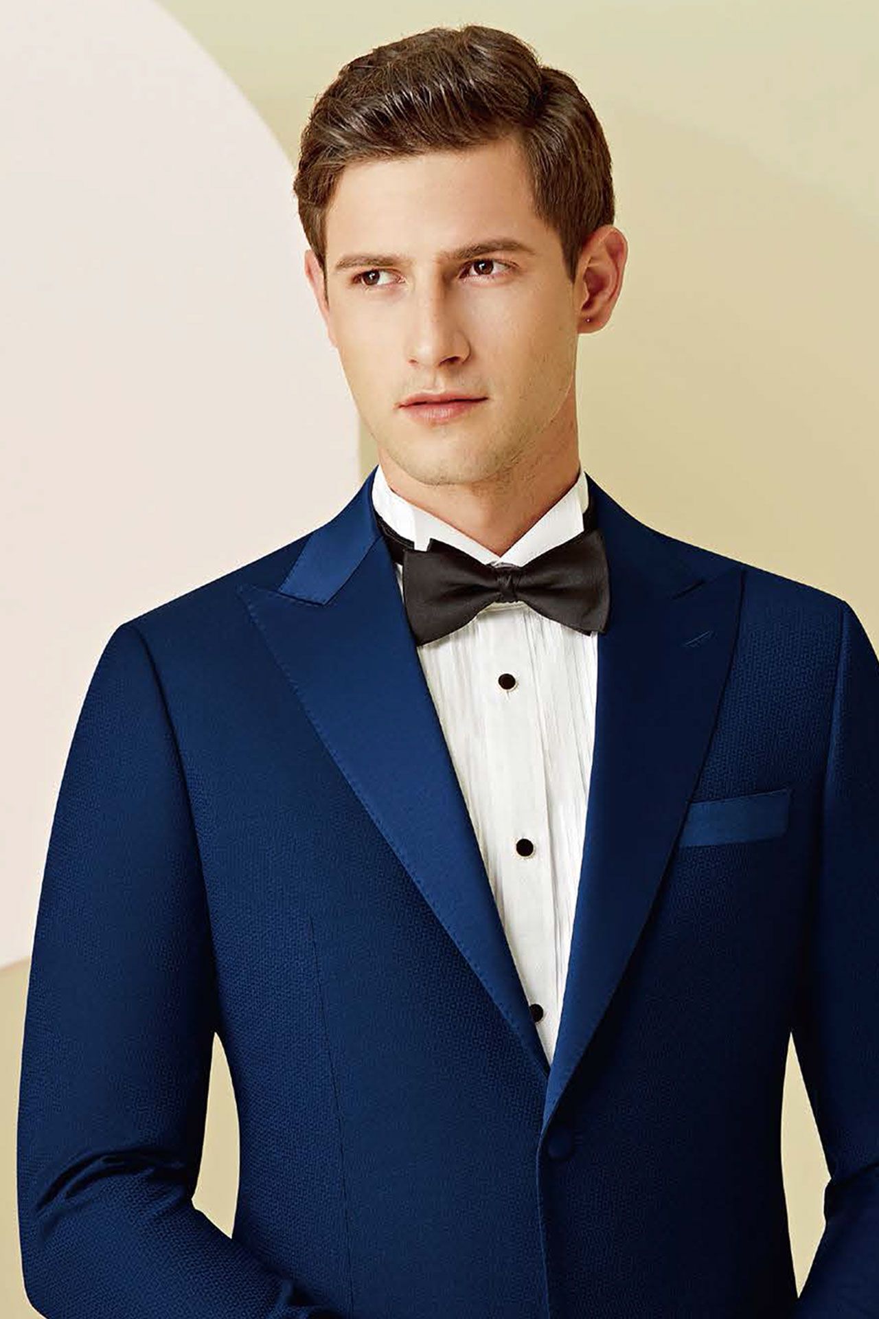 A man is wearing a blue tuxedo and a black bow tie