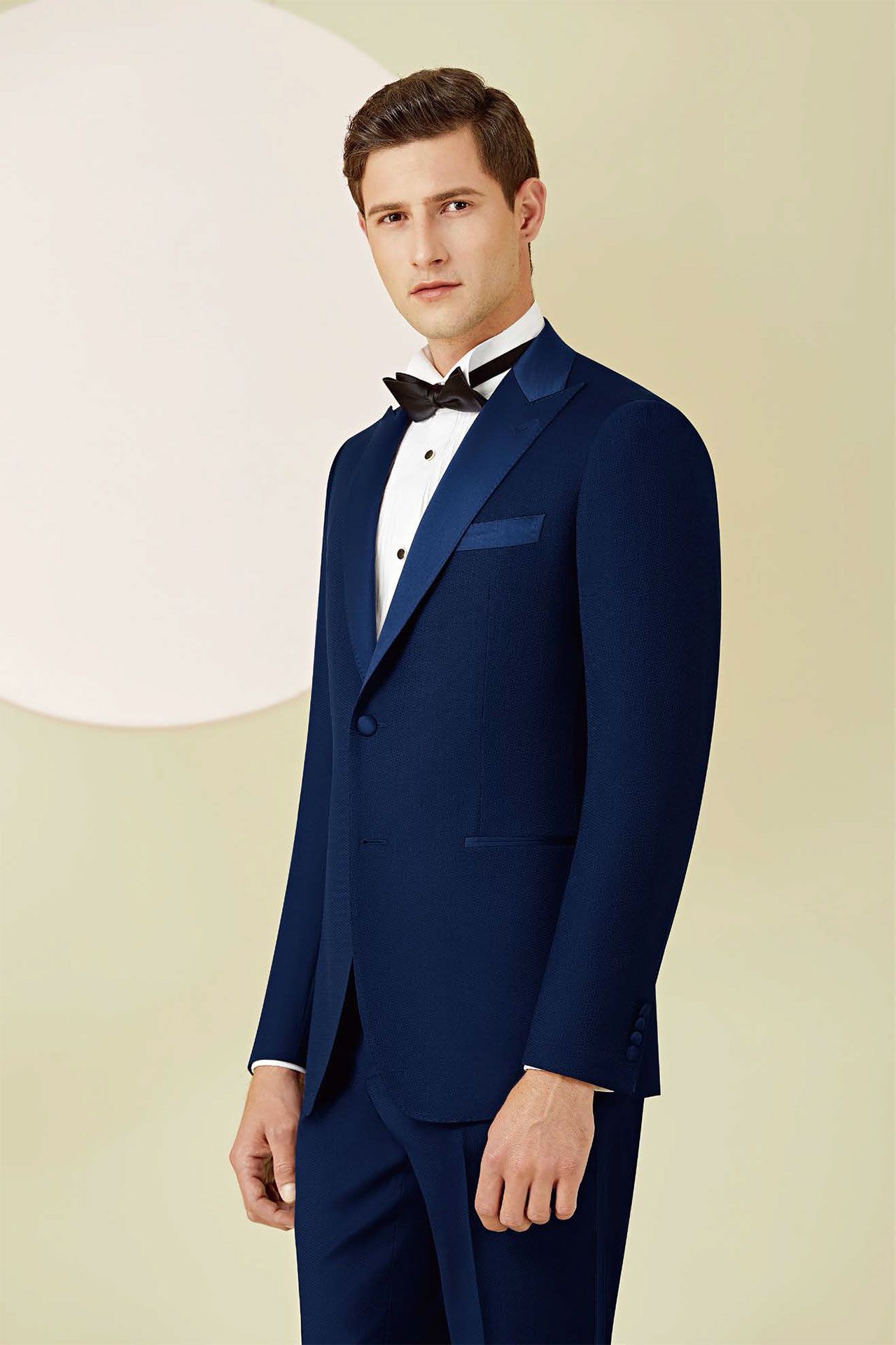 A man is wearing a blue tuxedo and bow tie